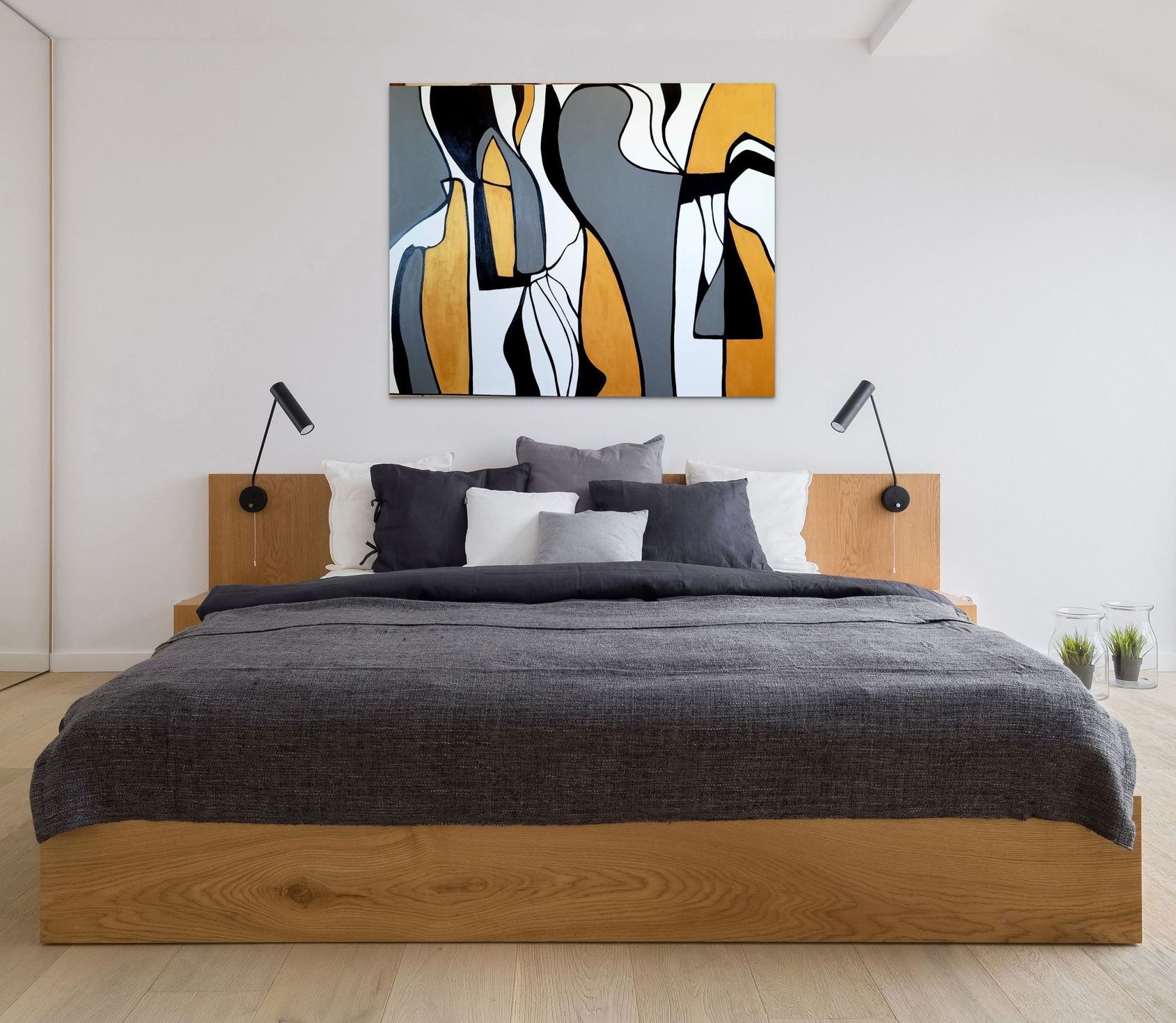 A modern bedroom featuring a wooden bed, gray bedding, and a large abstract painting in gold, gray, black, and white.