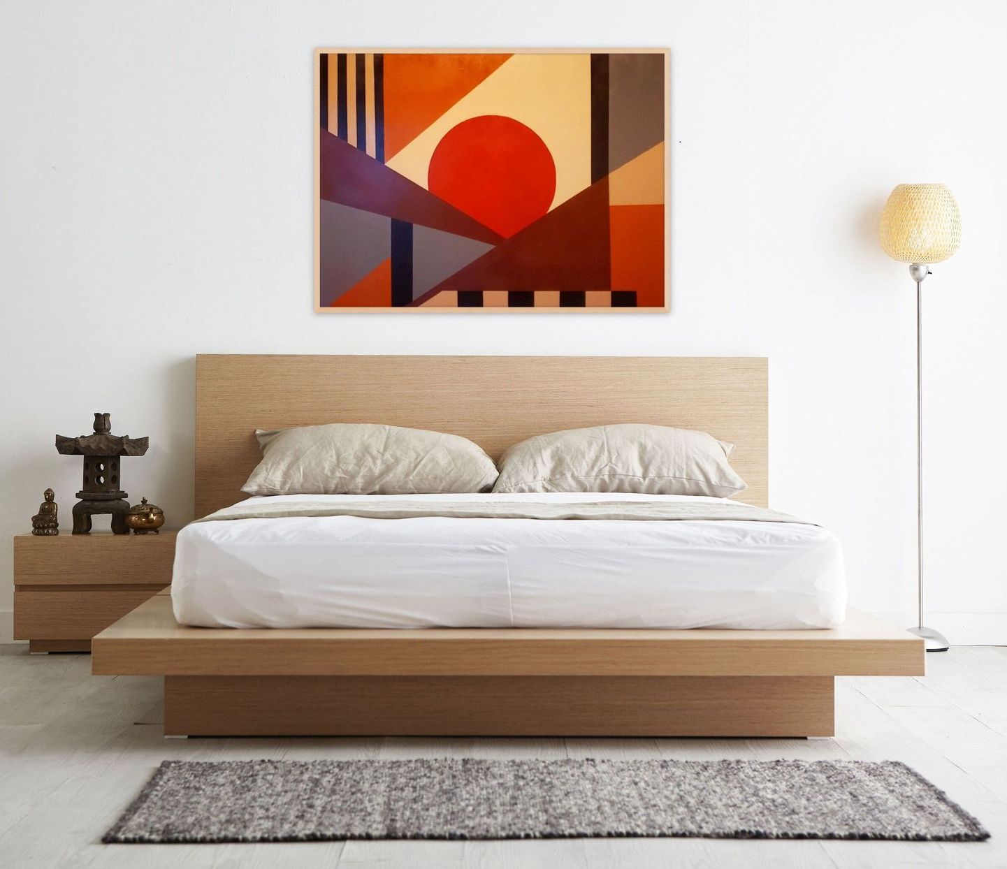 A modern bedroom with a low wood bed, a minimalist abstract art piece on the wall, and a floor lamp on the right.