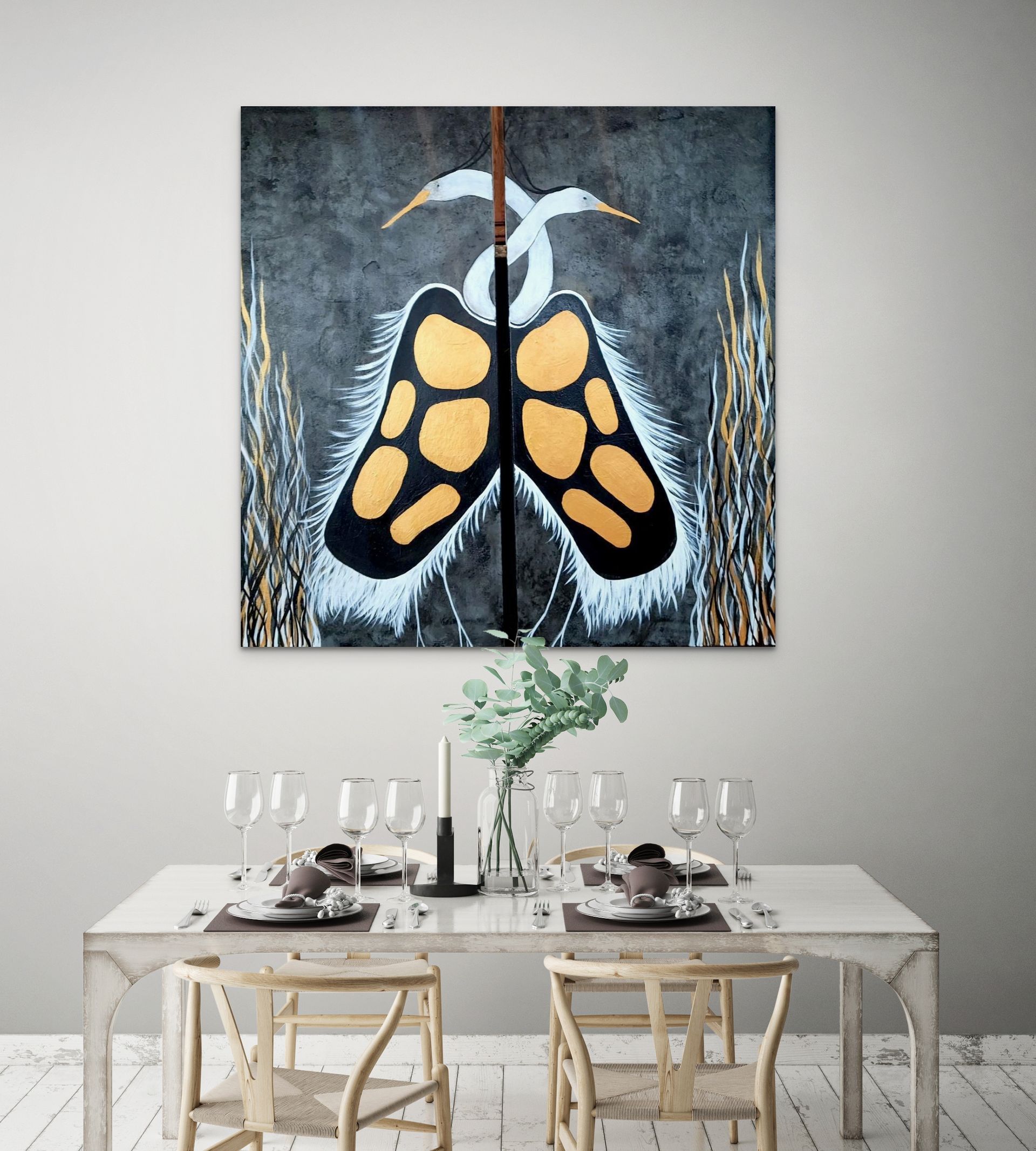 Two painted white herons with gold accents hang above a dining room table set for four in a modern home.