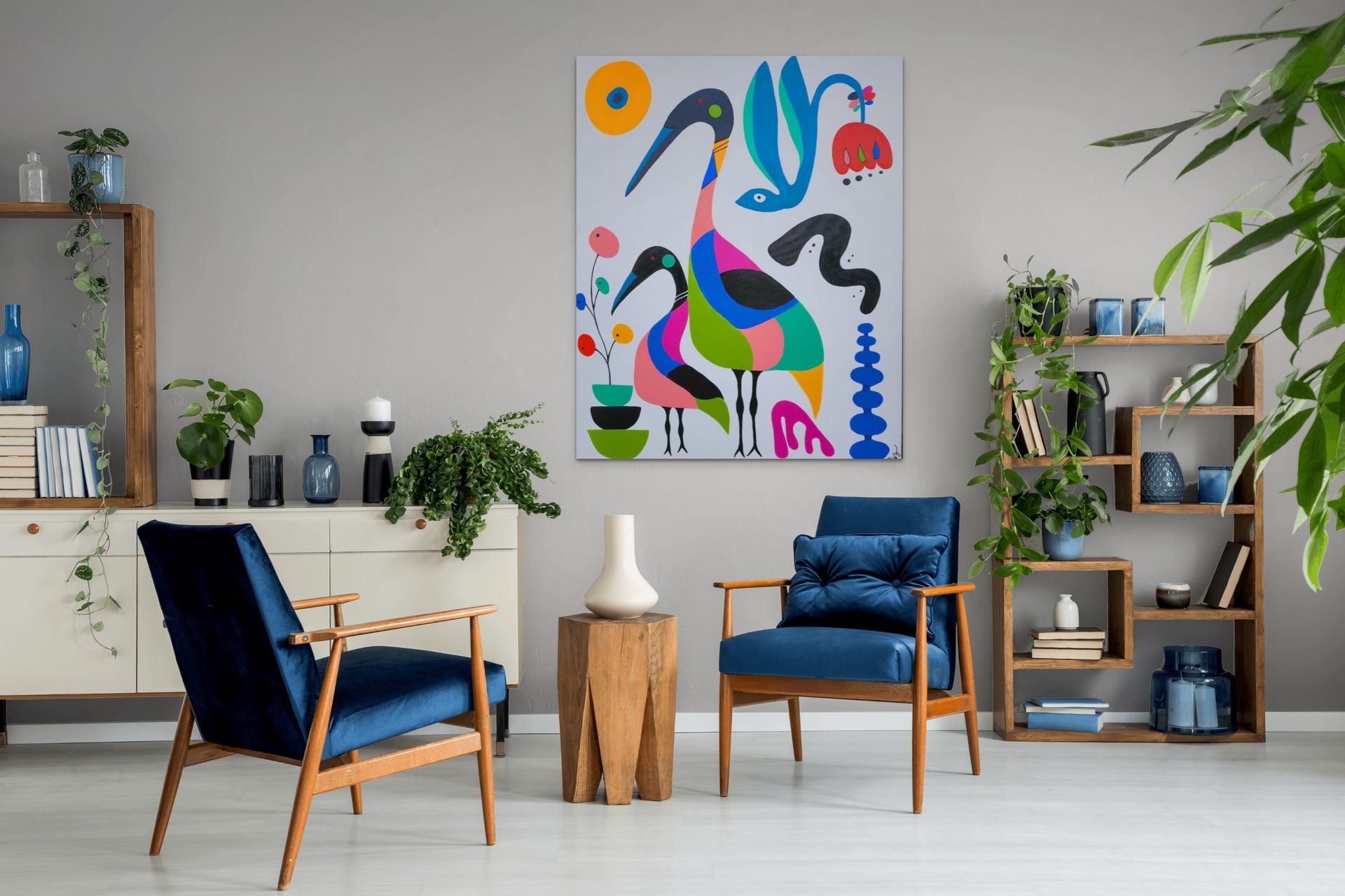 Two blue mid-century armchairs face each other in a modern living room with a colorful, abstract bird painting on the wall.