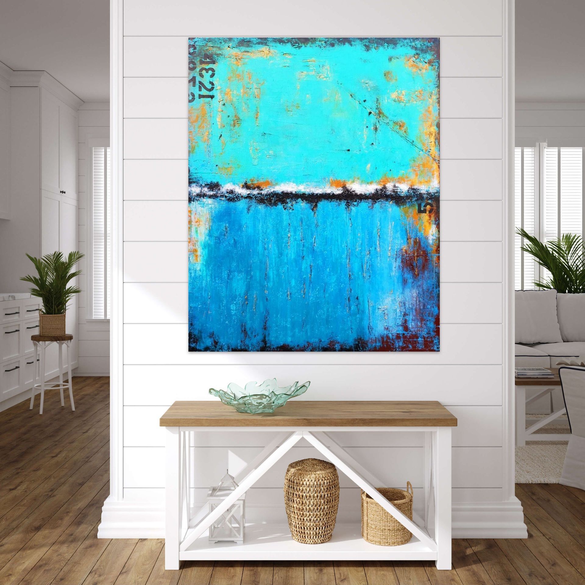 An abstract painting featuring bright blue and turquoise horizontal bands hangs on a white wall above a wooden table.