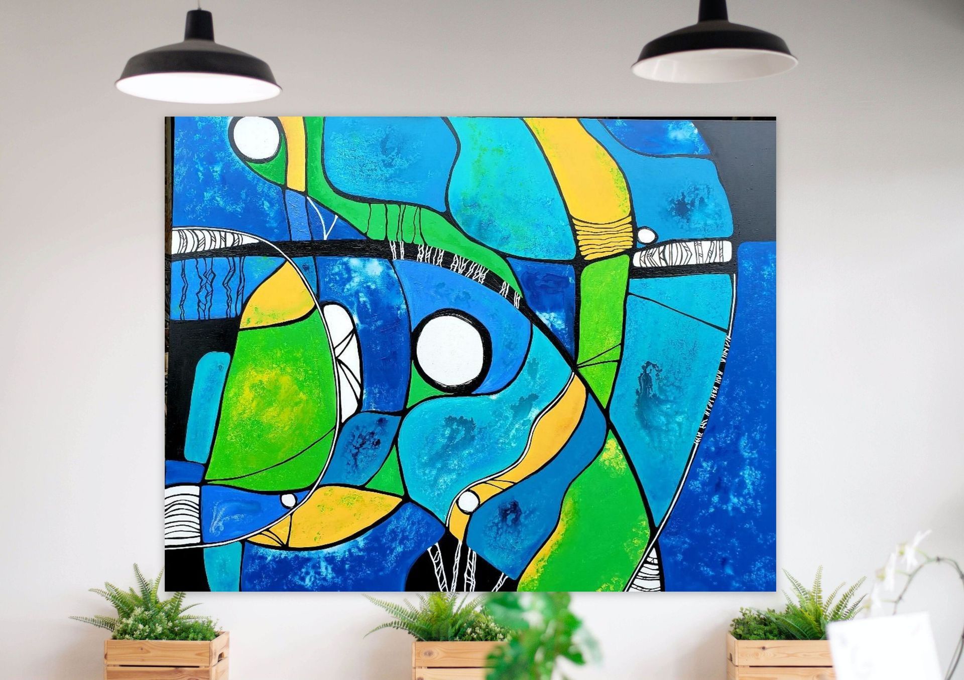 An abstract painting with vibrant blue, green, and yellow curved shapes hanging on a white wall above three potted plants.