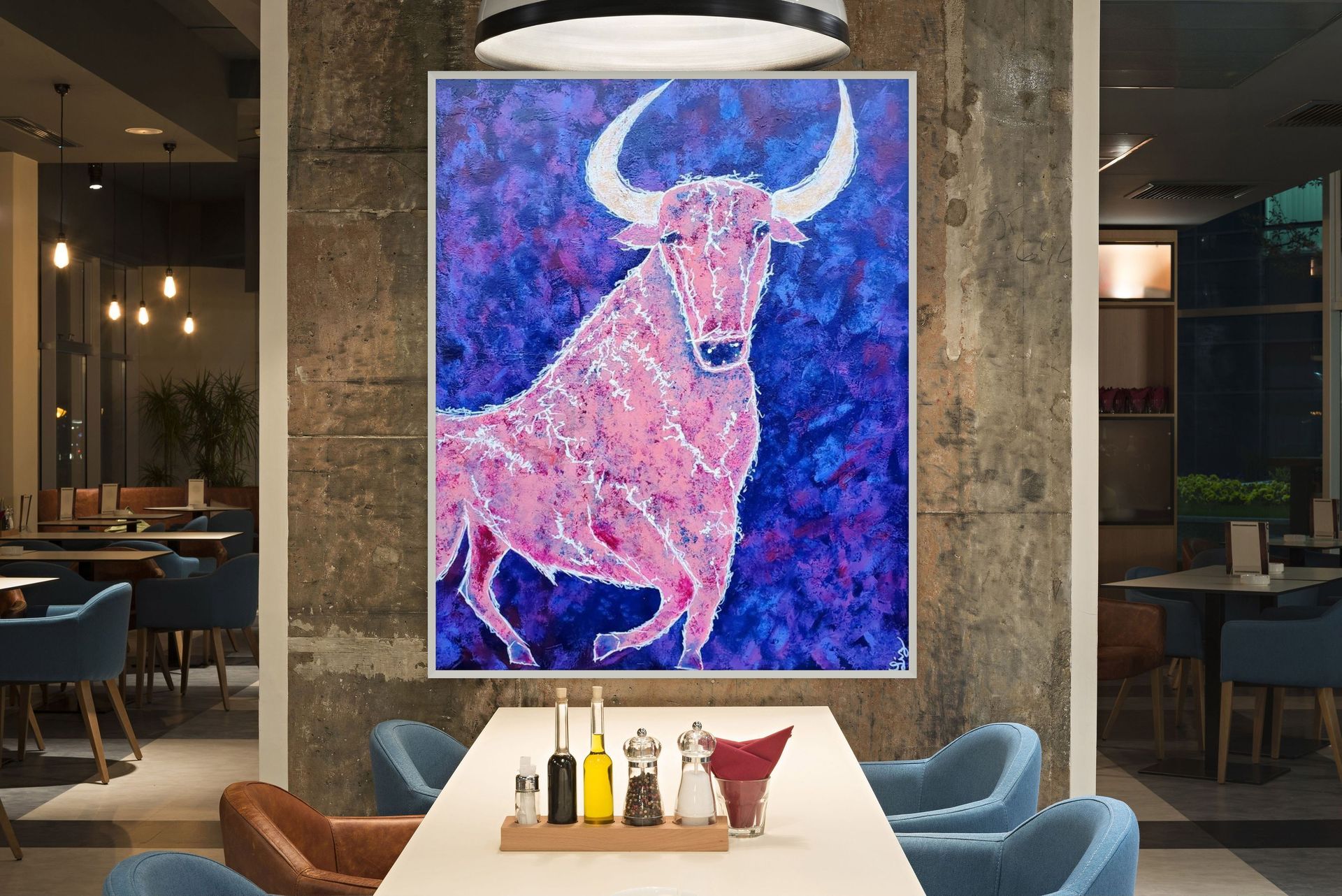 A painting of a pink bull with white horns on a purple background, displayed on a wall in a contemporary restaurant.