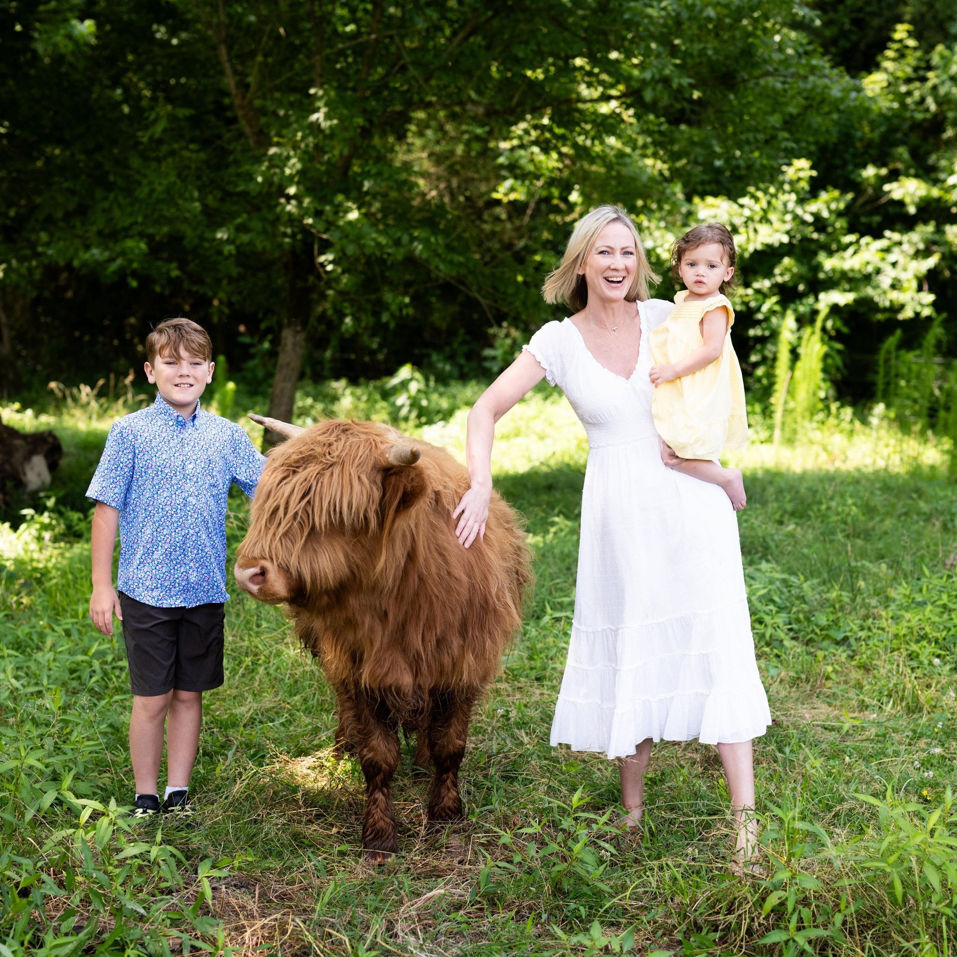 A woman and two children standing next to a brown cow