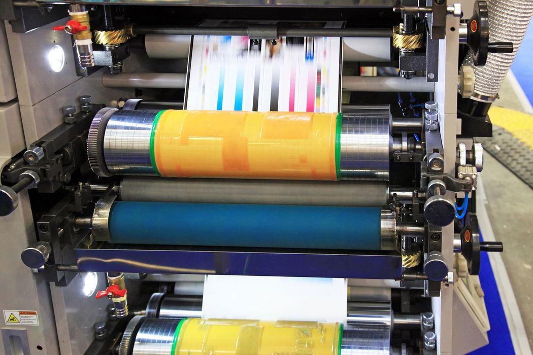 Macchina da stampa con rotoli di carta colorata che scorrono attraverso i macchinari.