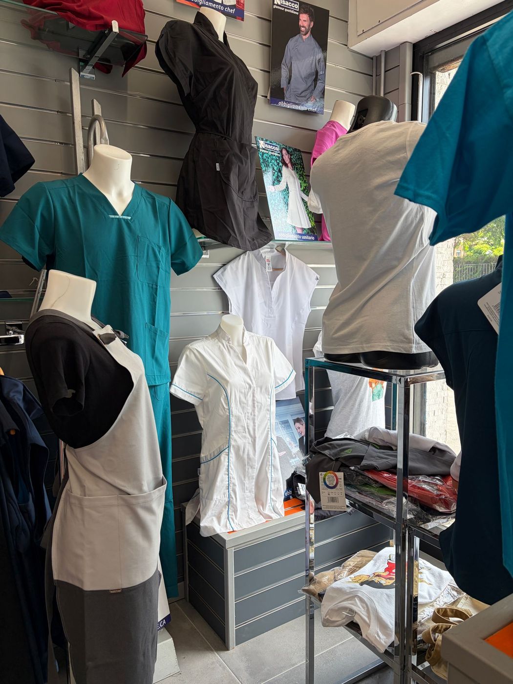 Manichini che indossano camicie color verde acqua, bianche e nere in una vetrina di un negozio di abbigliamento.