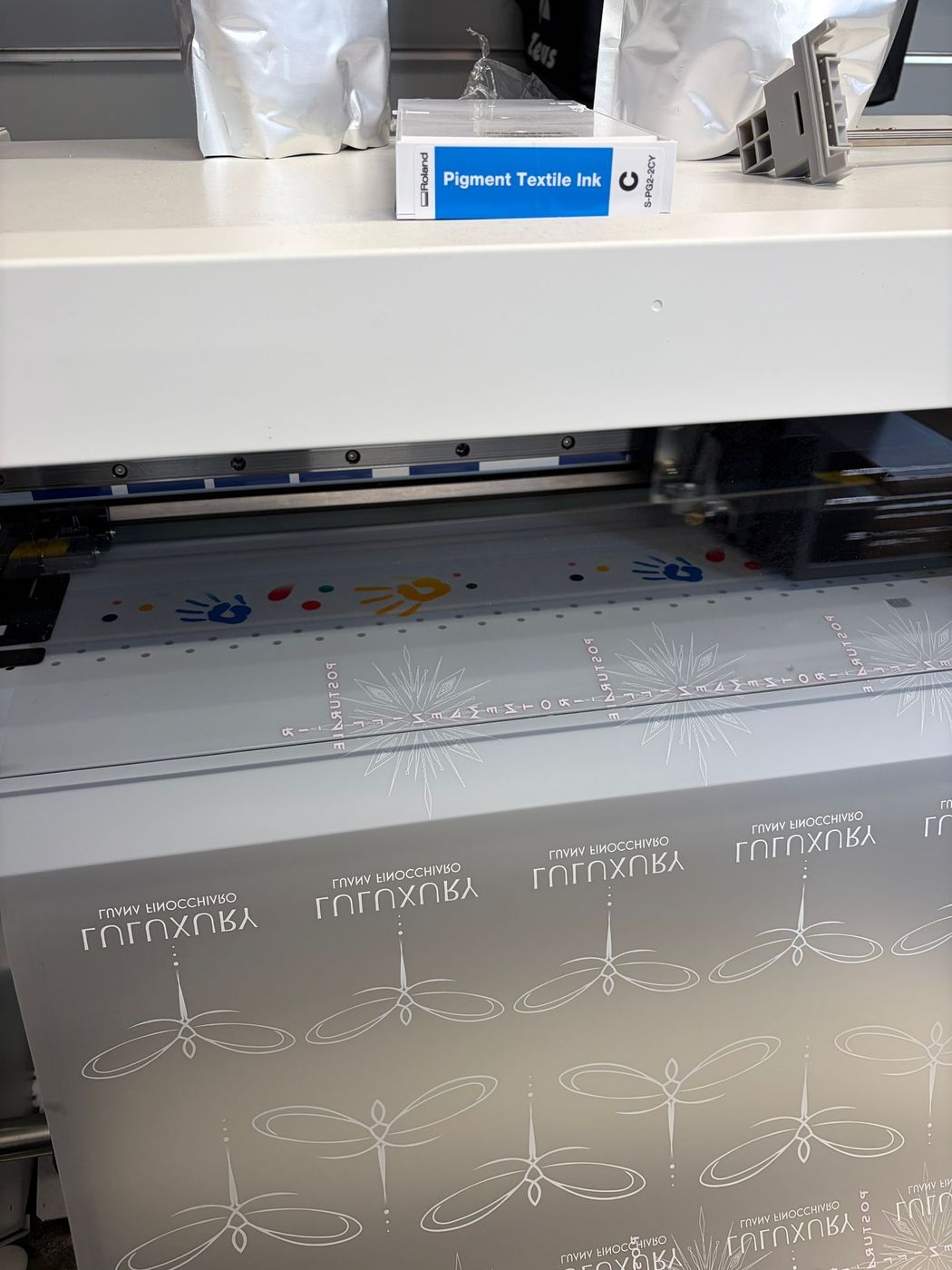 Una stampante 3D in un'officina, intenta a stampare un foglio grigio con un motivo a rilievo sotto la testina di stampa.