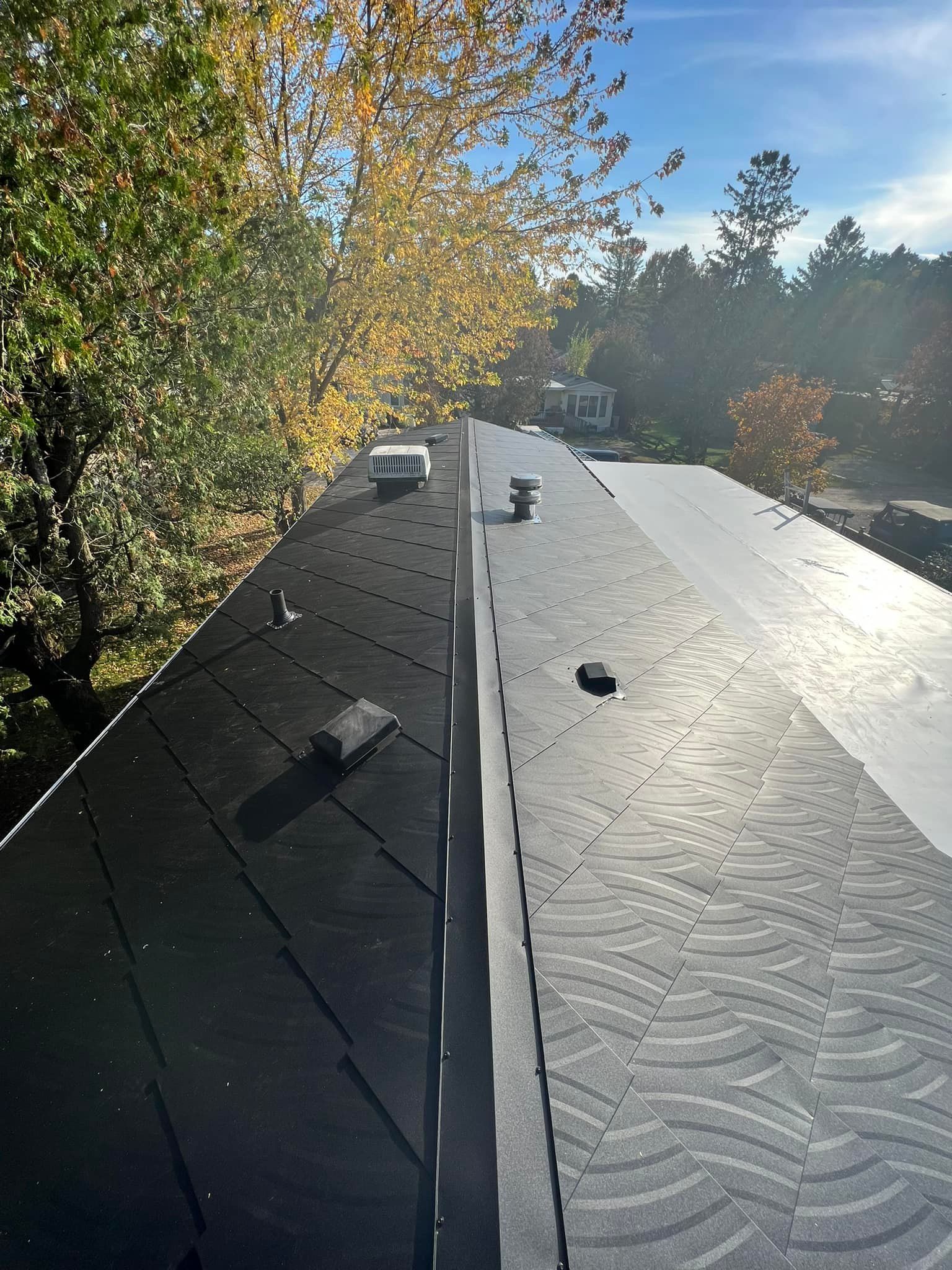 A black roof with trees in the background and a blue sky in the background.
