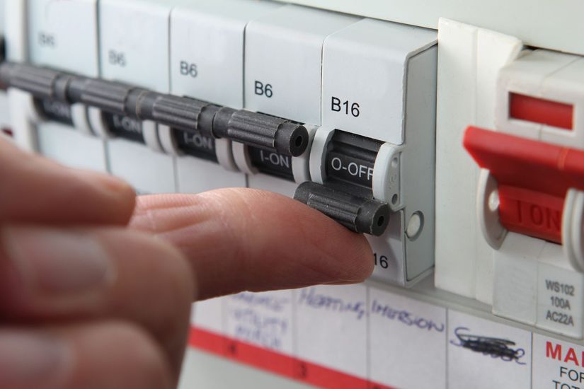A hand flips a B16 circuit breaker switch from the 'OFF' position to 'ON' in a home electrical consumer unit.
