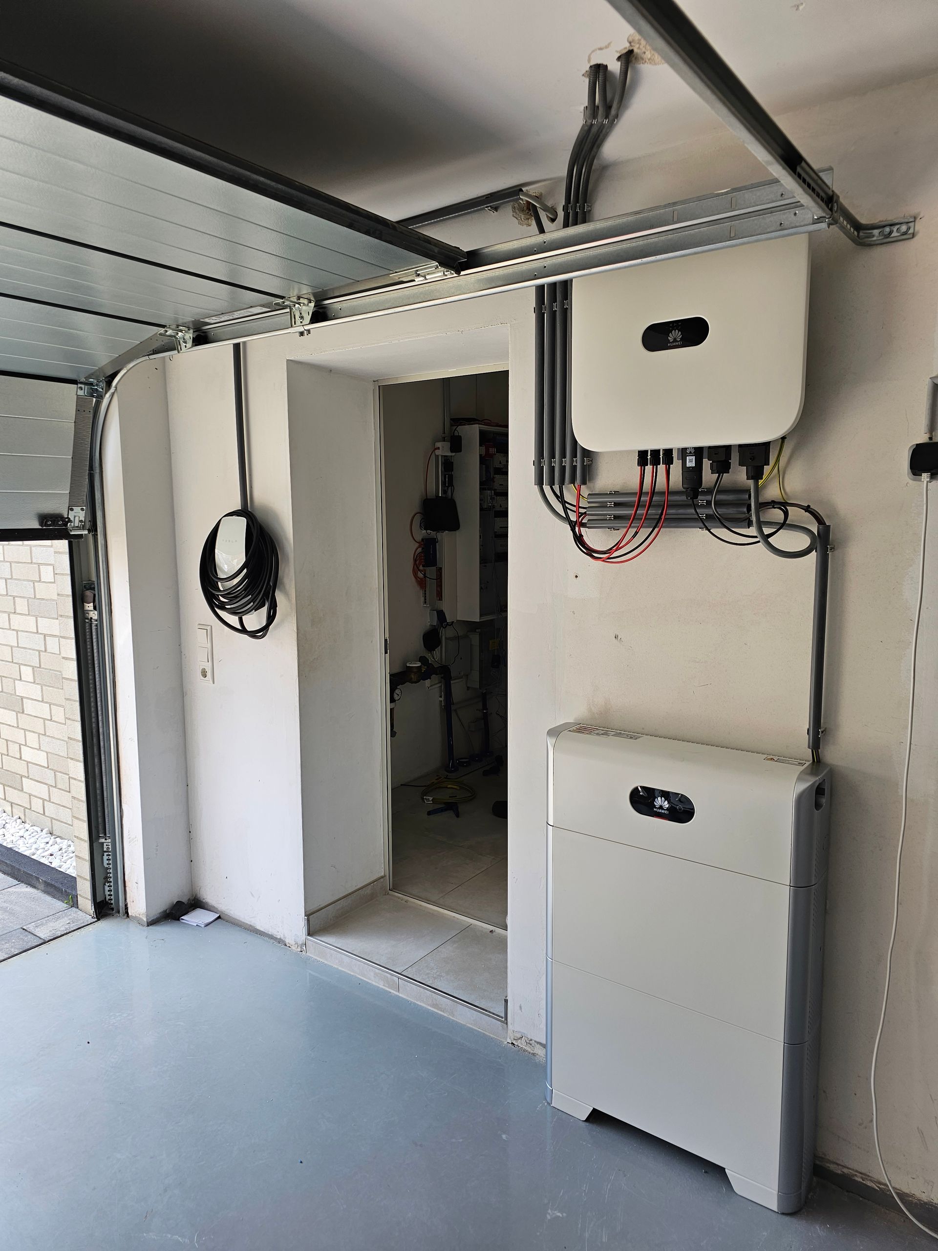 Een garage met een open deur en een zonnepaneel aan de muur.