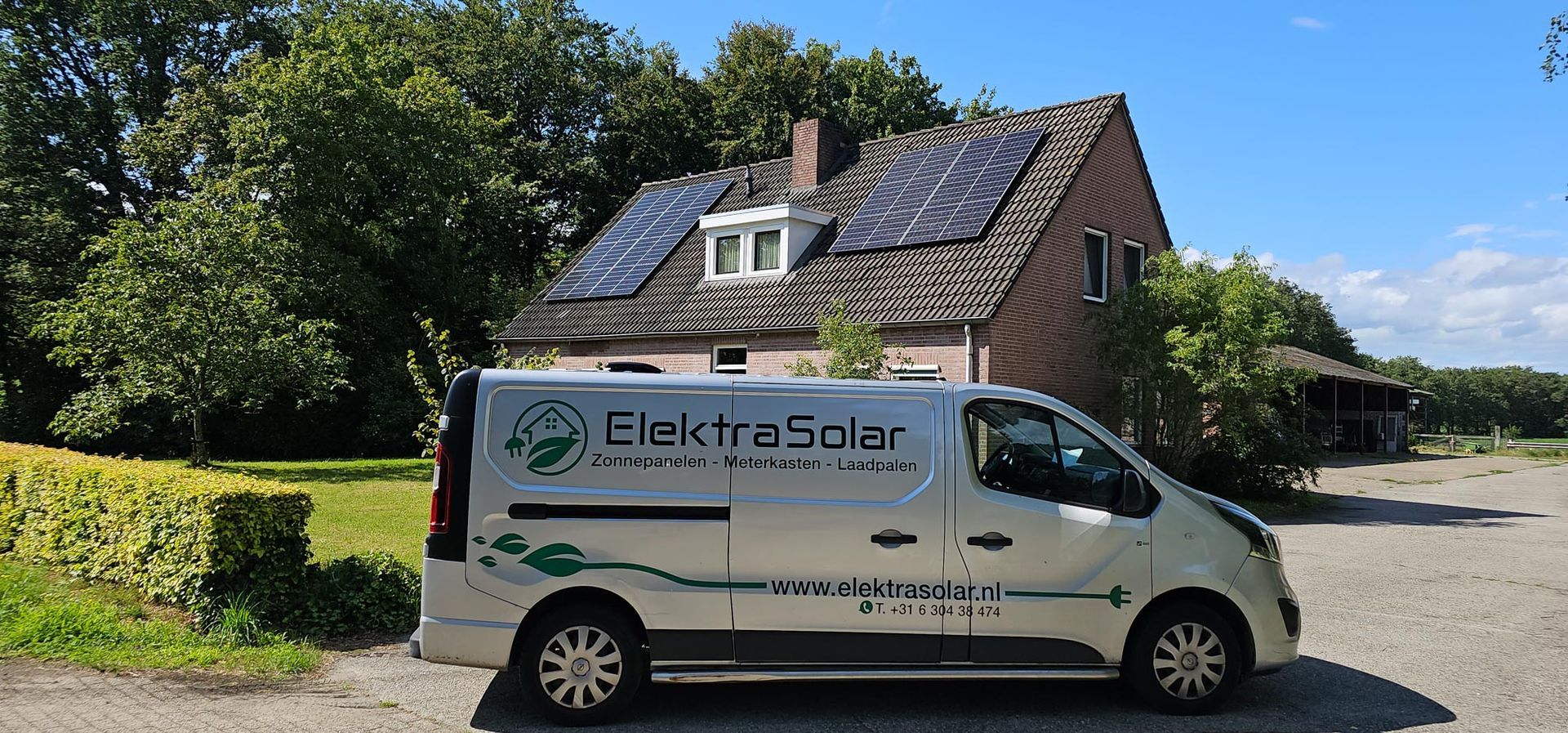 Een witte bestelwagen staat geparkeerd voor een huis met zonnepanelen op het dak.