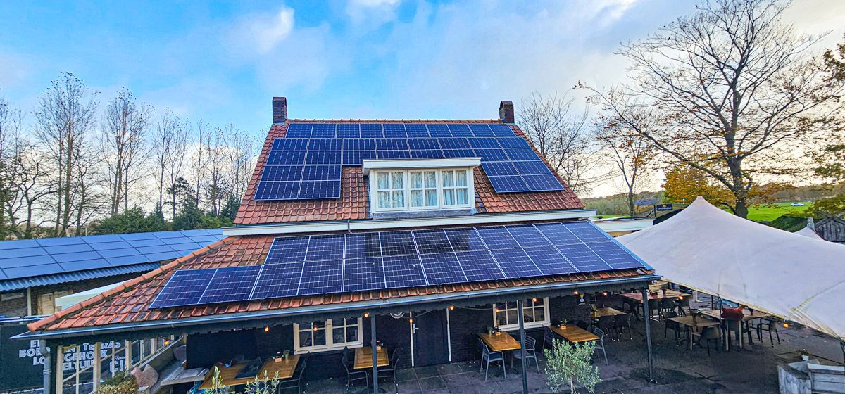 Een groot huis met veel zonnepanelen op het dak.