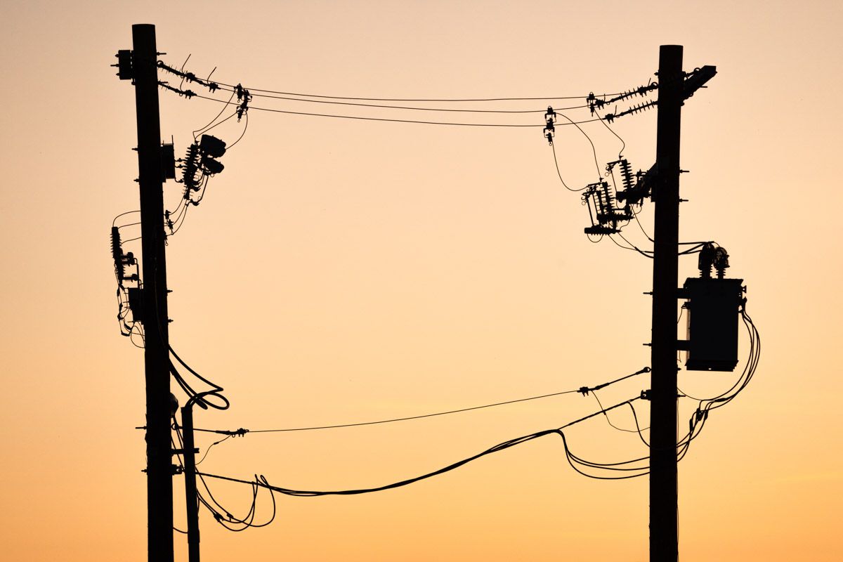 Een silhouet van een elektriciteitsleiding met een zonsondergang op de achtergrond