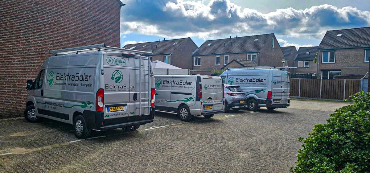 Een rij busjes geparkeerd op een oprit voor een bakstenen gebouw.