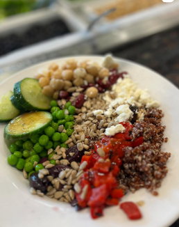 Salad bowl with chickpeas, cucumbers, peas, quinoa, feta, sunflower seeds, and red peppers.