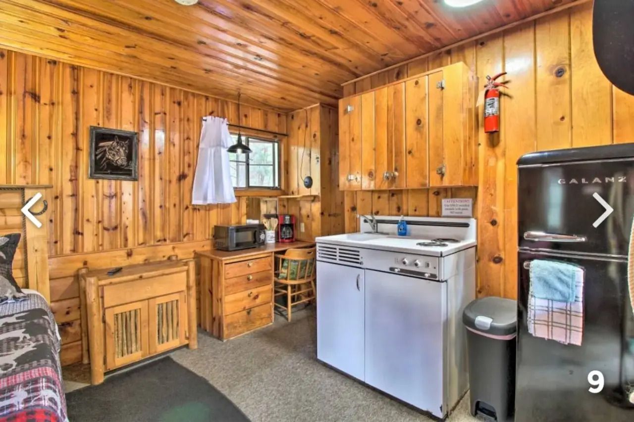 Wood-paneled cabin kitchen with stainless stove, sink, refrigerator, and small window.