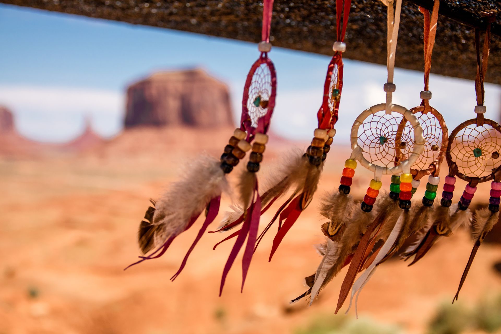 Dreamcatcher-style ornaments with feathers hanging against a blurred desert landscape