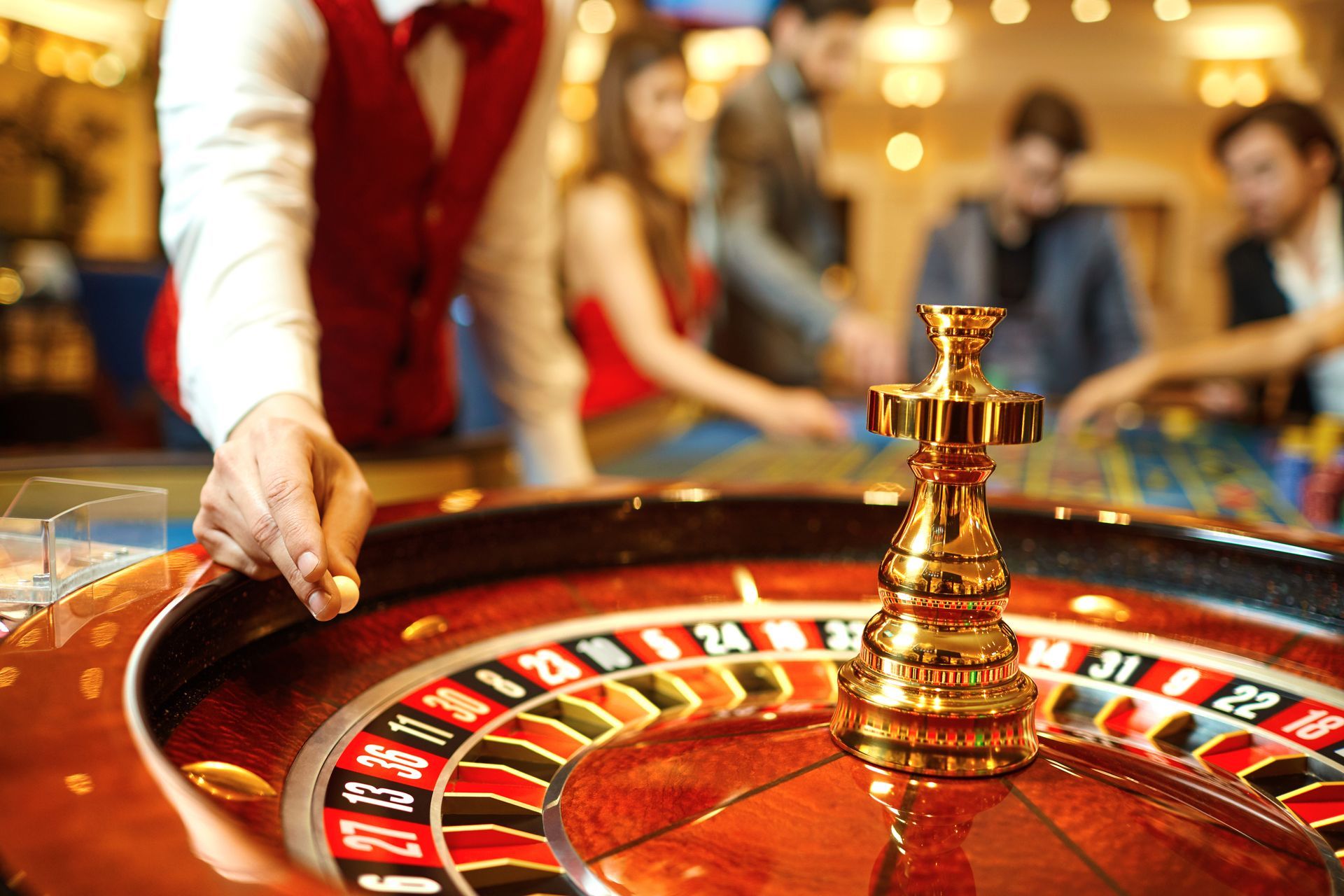 Roulette wheel in a casino, with a dealer spinning the ball beside a golden center spindle
