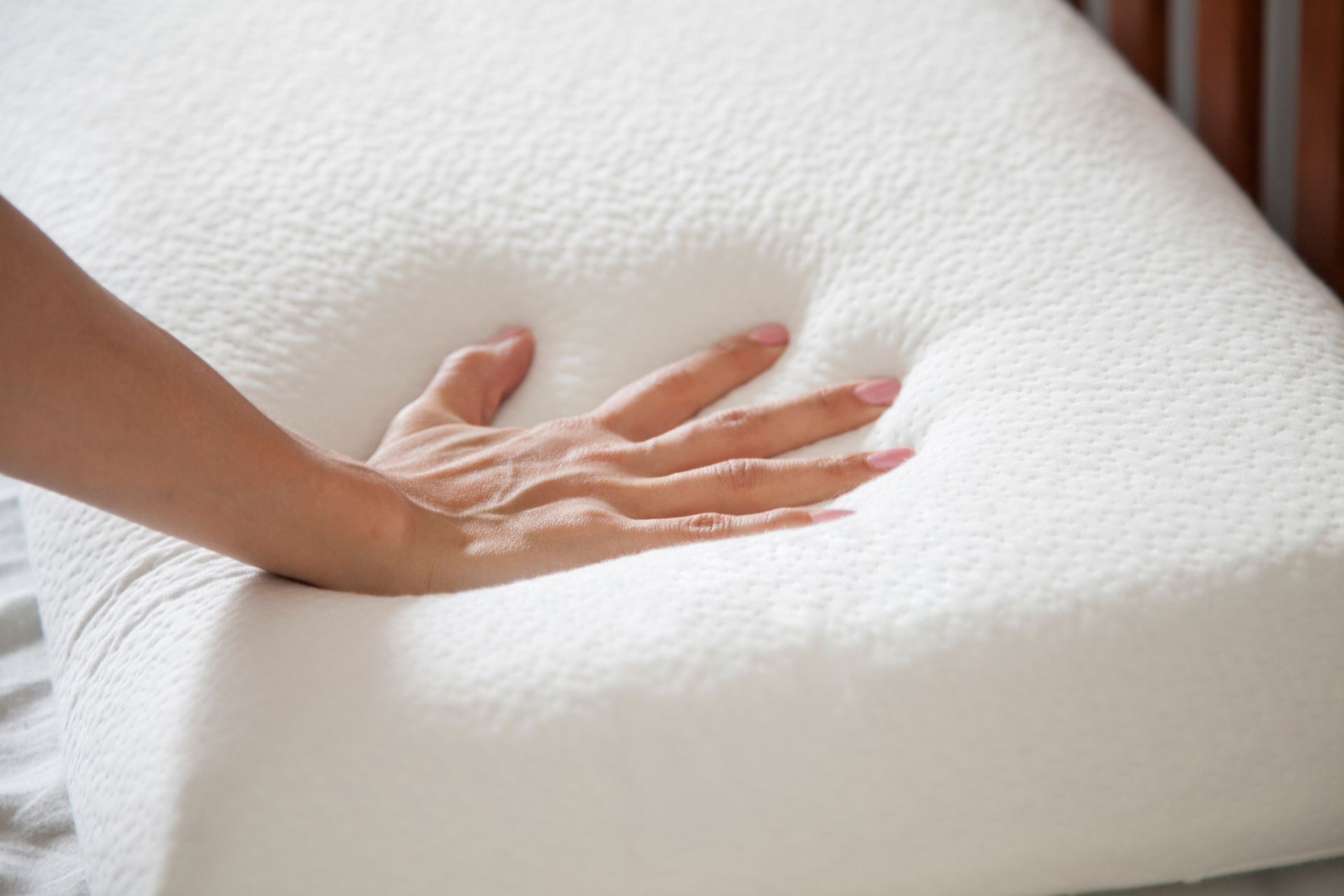 Hand pressing into a white foam mattress, showing softness and support