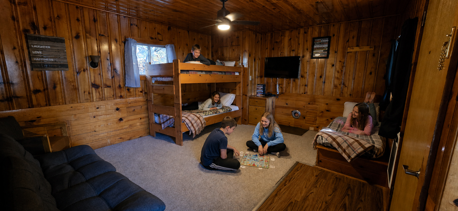 Cozy wooden cabin bedroom with bunk beds and three people sitting on the floor and bed nearby