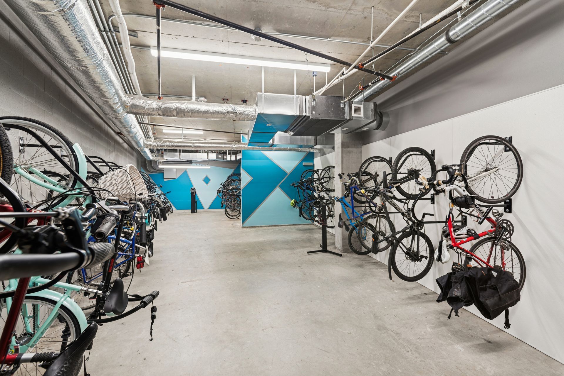 Indoor bike storage room with rows of bicycles and blue geometric wall accents