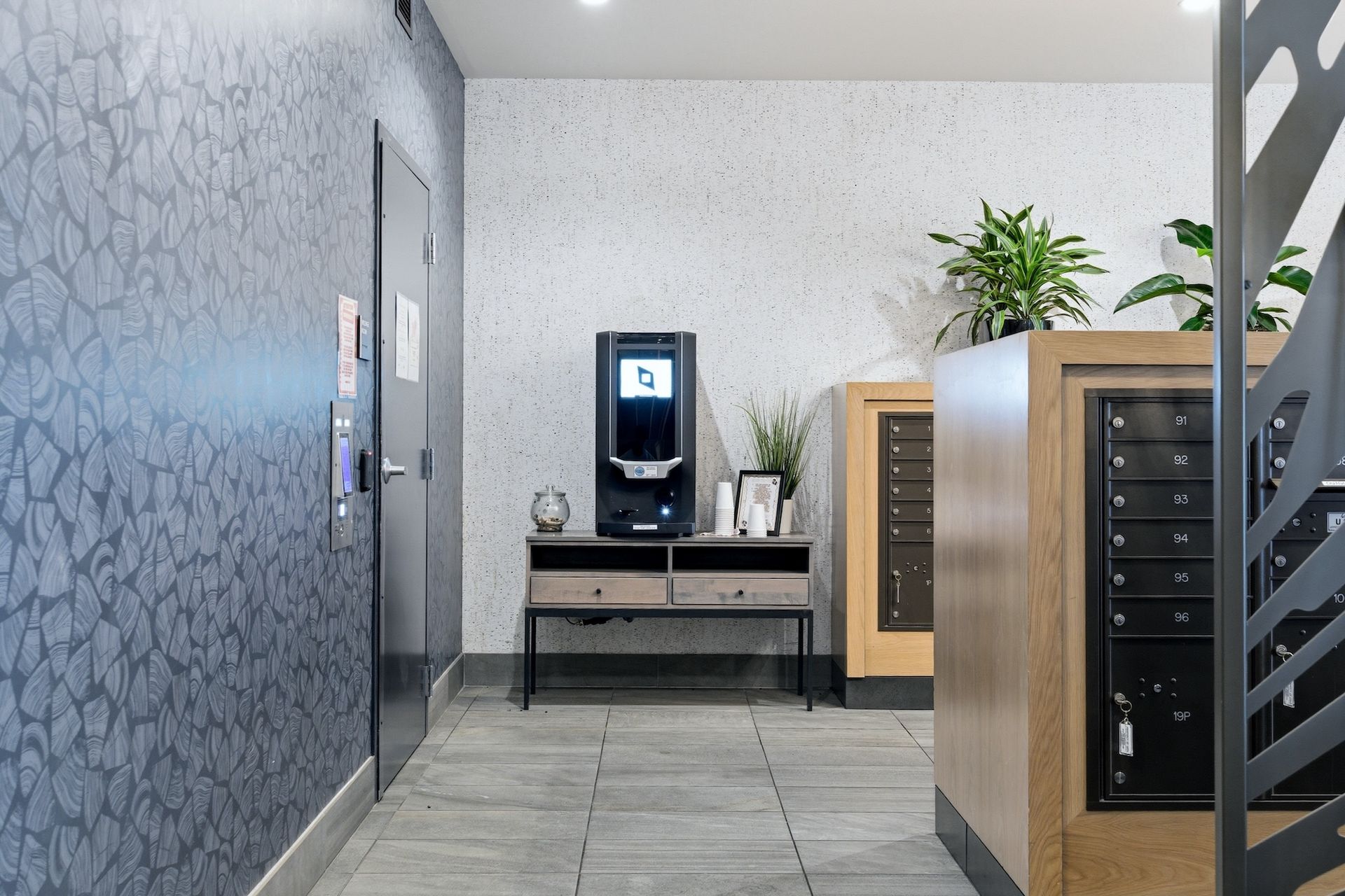Office lobby with coffee station, wooden cabinets, and a plant on a counter