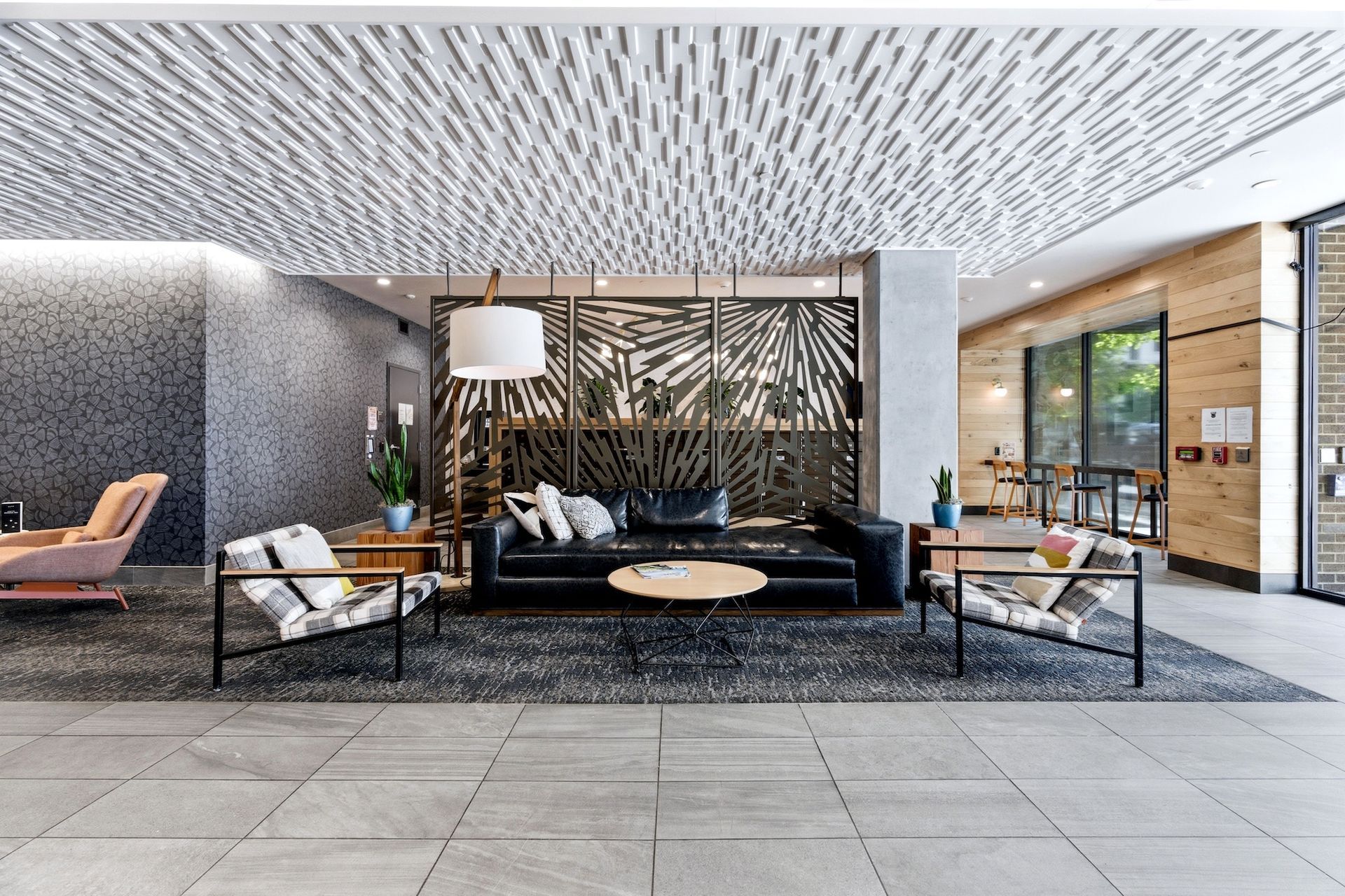 Modern lobby lounge with black-and-white seating, wood accents, and large glass entrance.