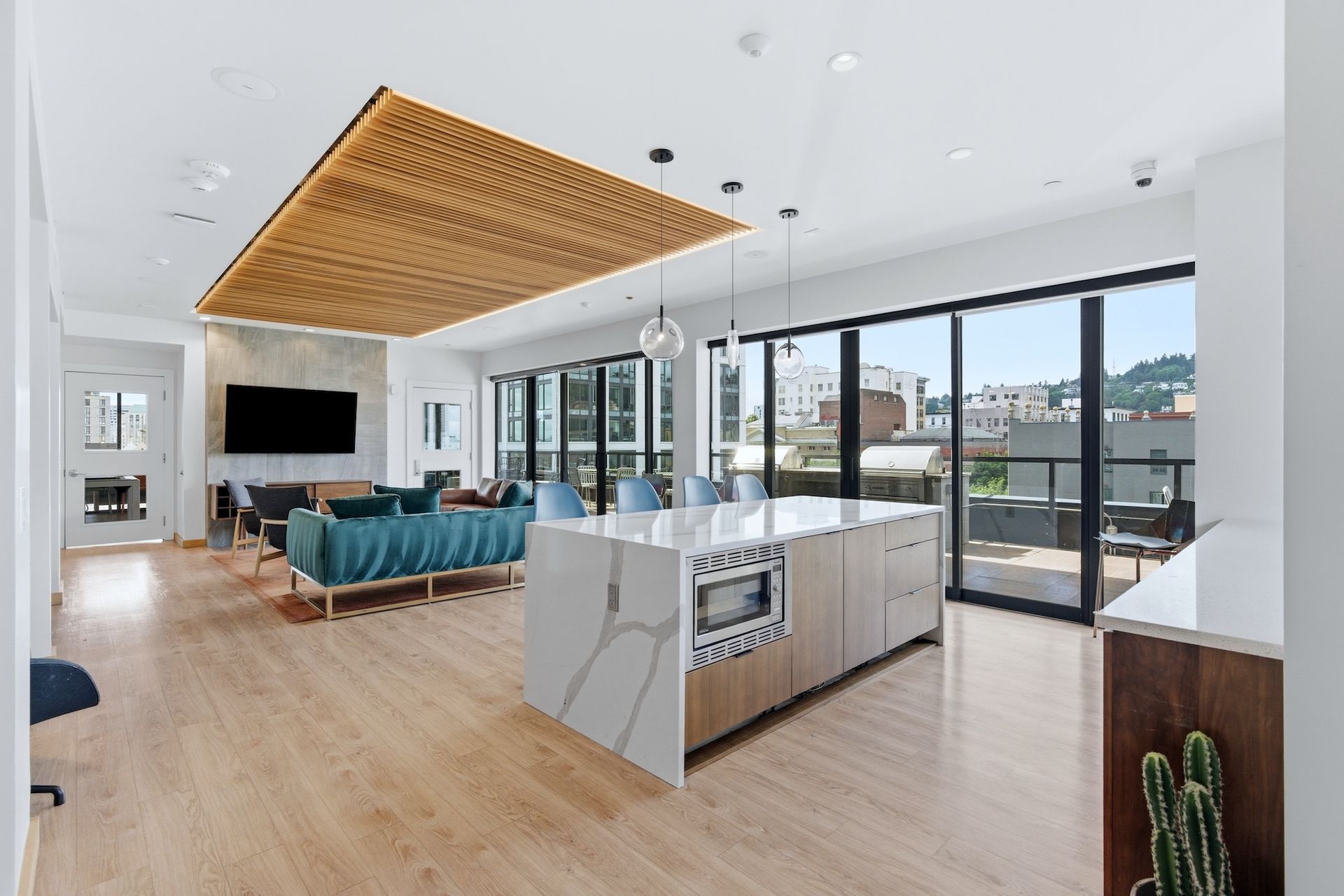 Modern open-plan living room and kitchen with large windows, wood floors, and a woven ceiling feature
