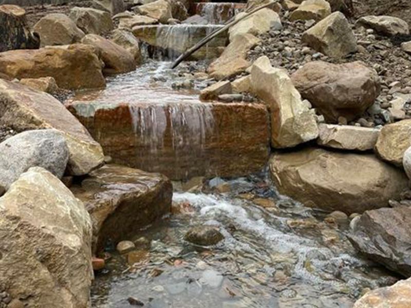 Rocky stream with a small waterfall flowing over stones in a natural creek bed