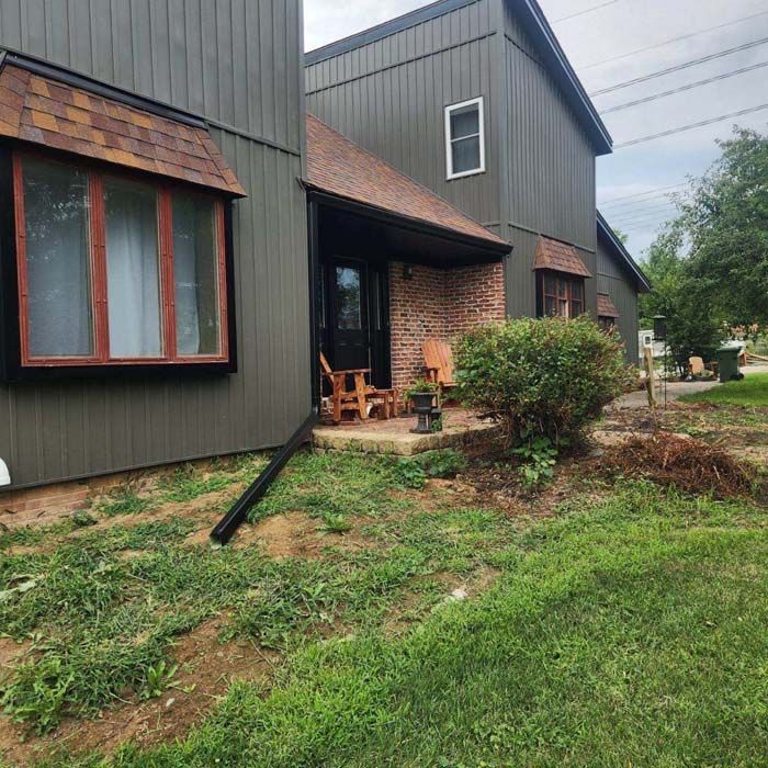 Exterior of a two-story house with green siding, brown trim, and a brick entrance.