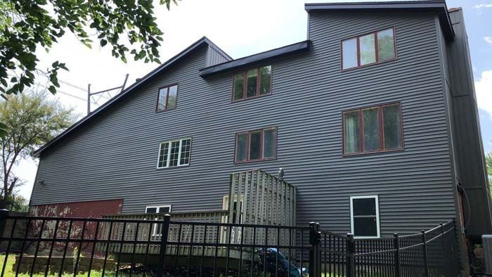 Dark gray house with multiple windows and a black fence.