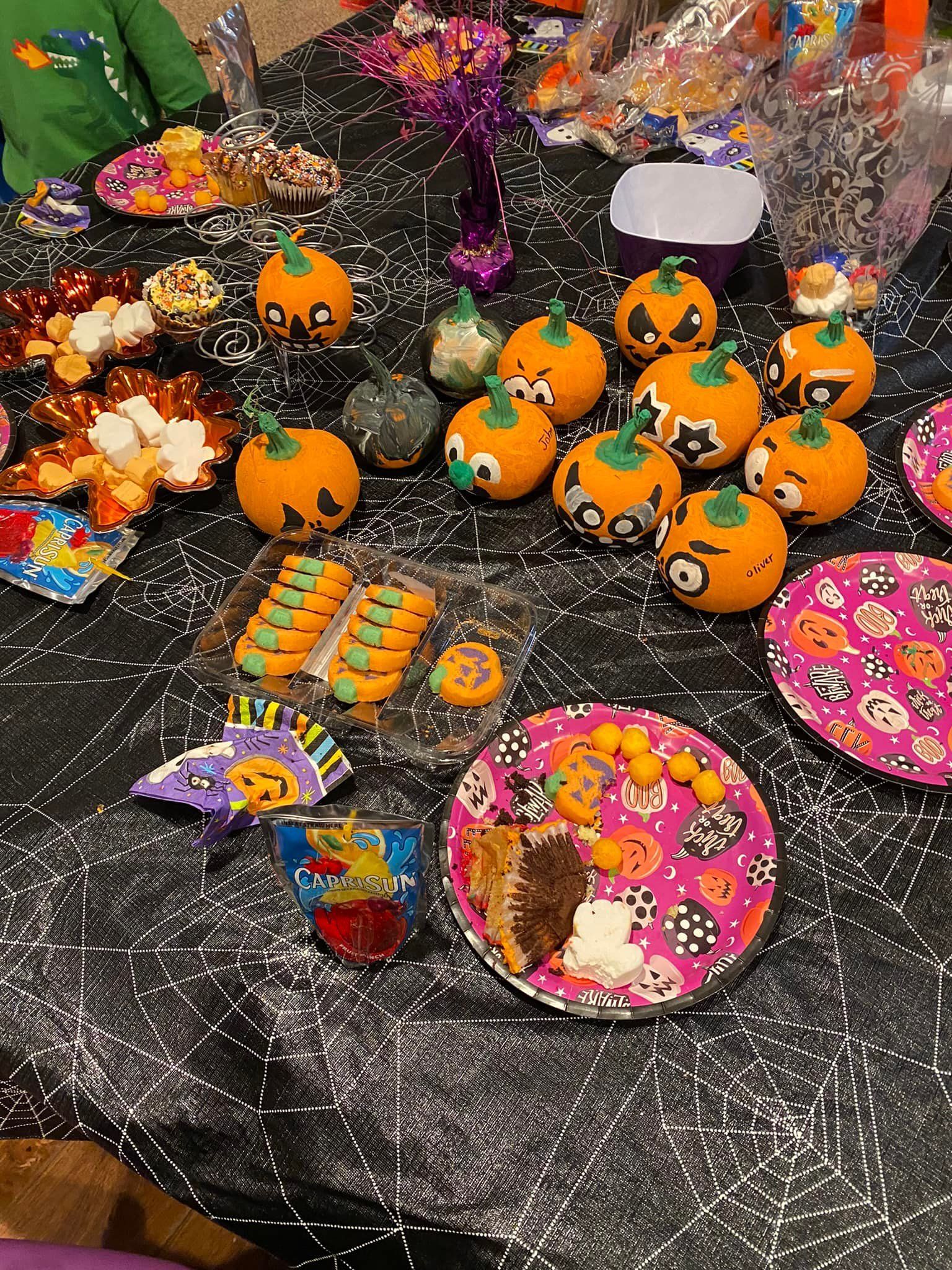 Assorted colorful Halloween-themed candies and snacks displayed on a table with black netting.