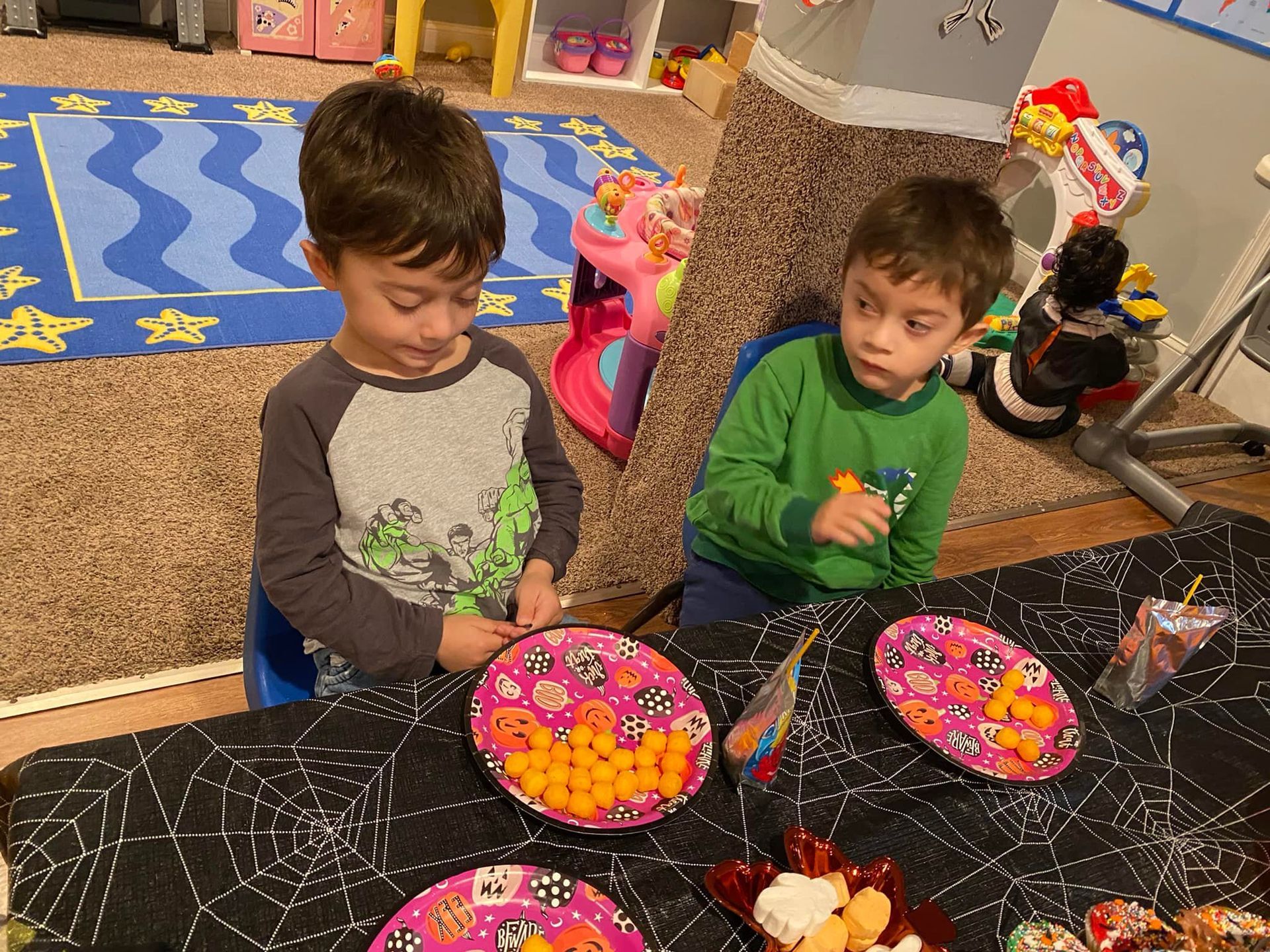 Two children at a table with colorful cupcakes and craft supplies, looking down while working together.