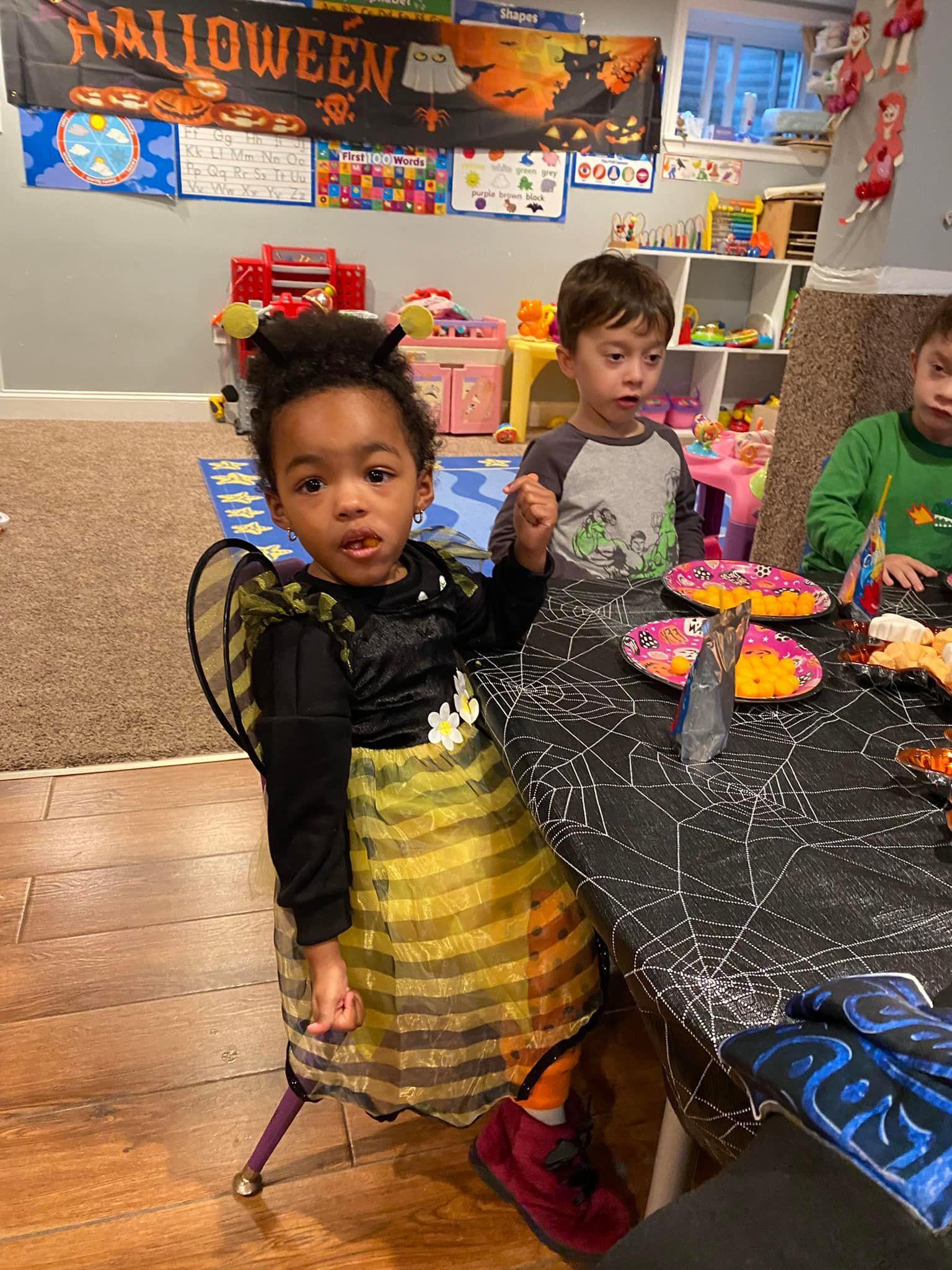 Children in Halloween costumes at a decorated party table with treats and crafts