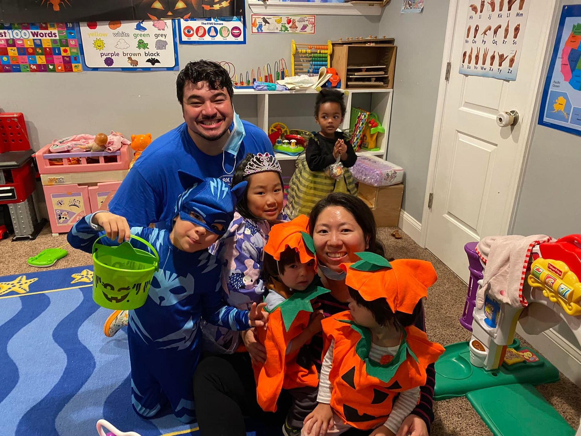 Group of people in colorful costumes posing in a classroom, smiling and kneeling together.