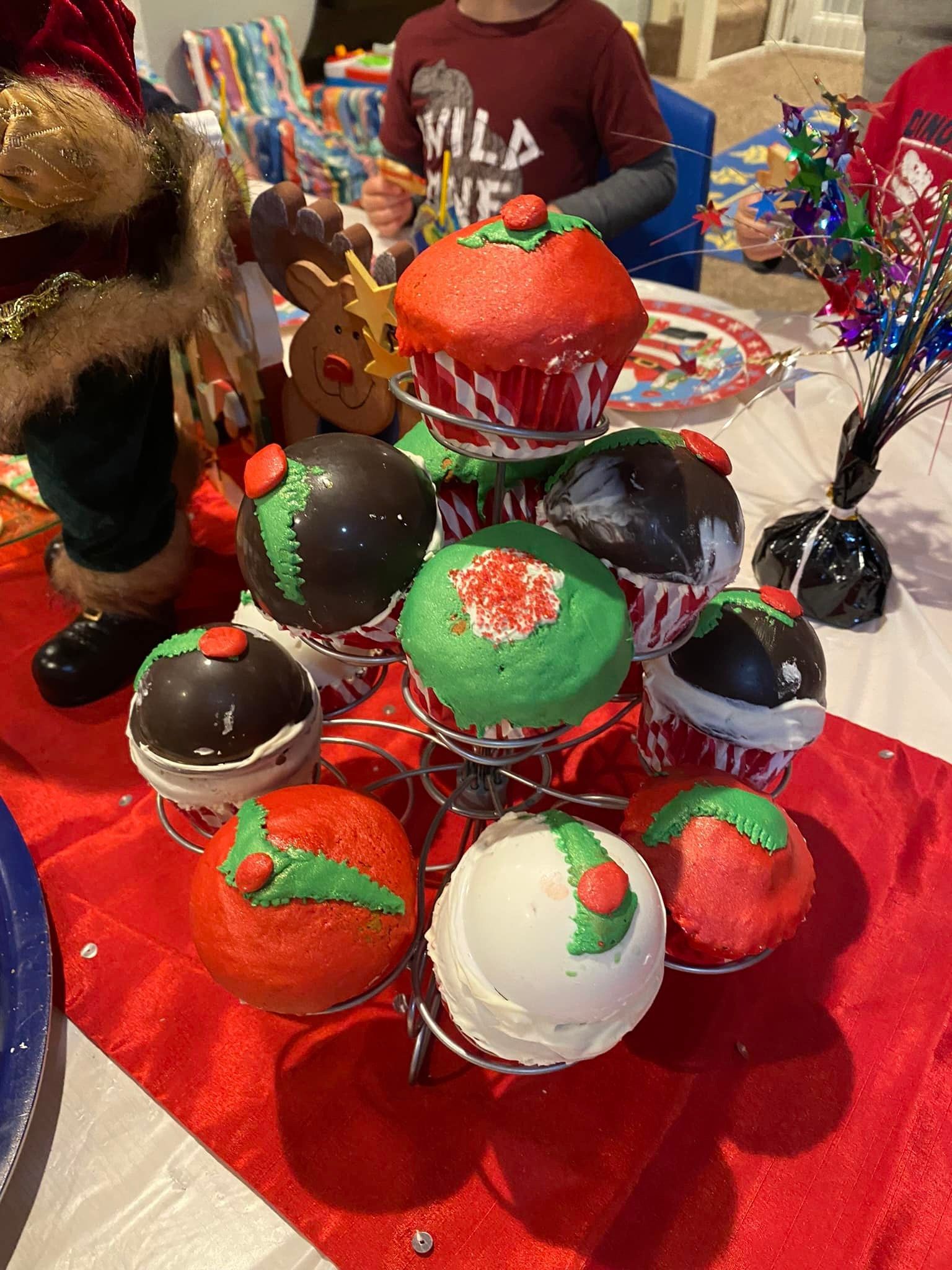 Decorated cake pops on sticks displayed on a red tablecloth at a festive party