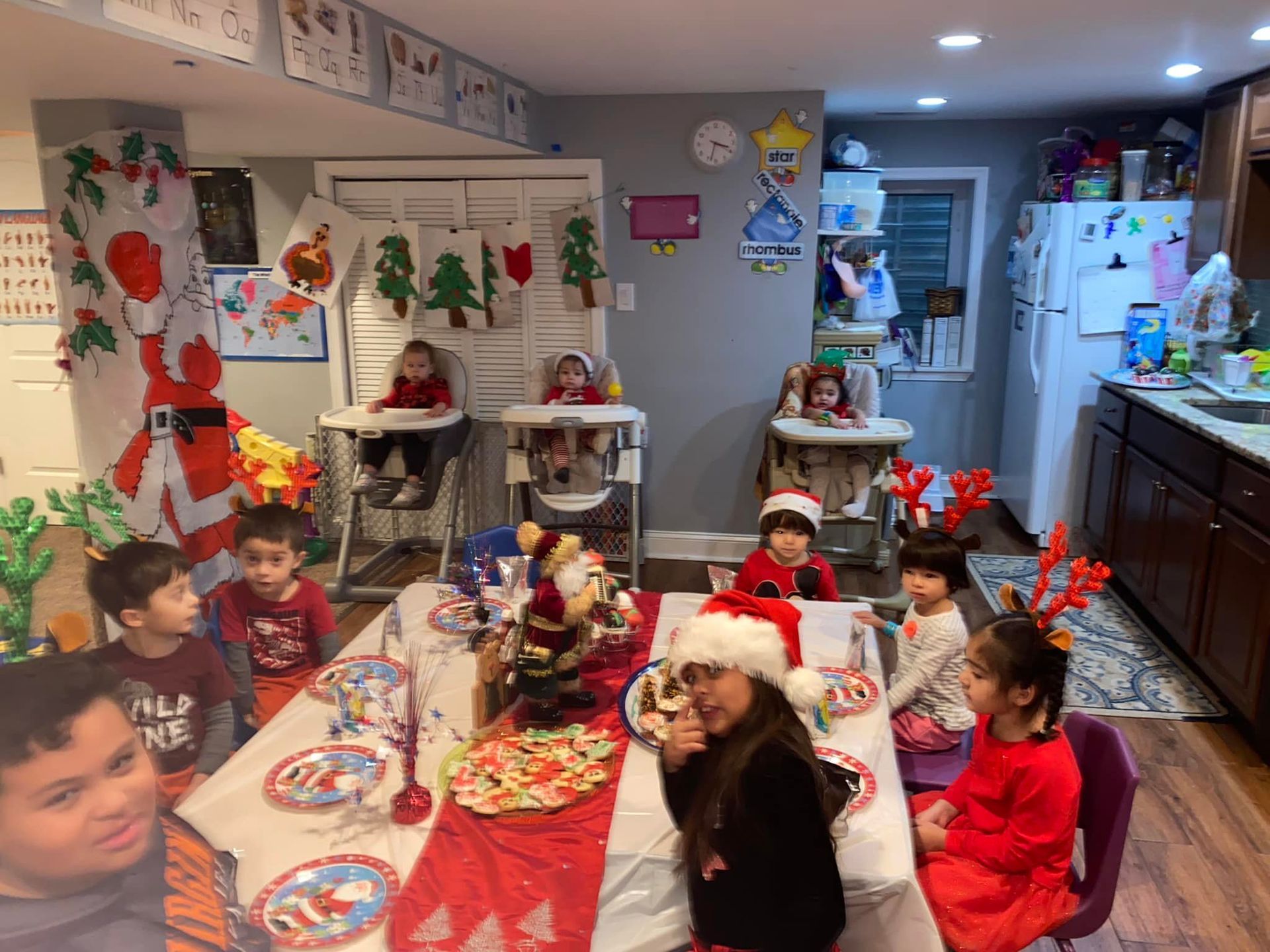 Children seated at a holiday table in a decorated dining room with Christmas crafts and treats