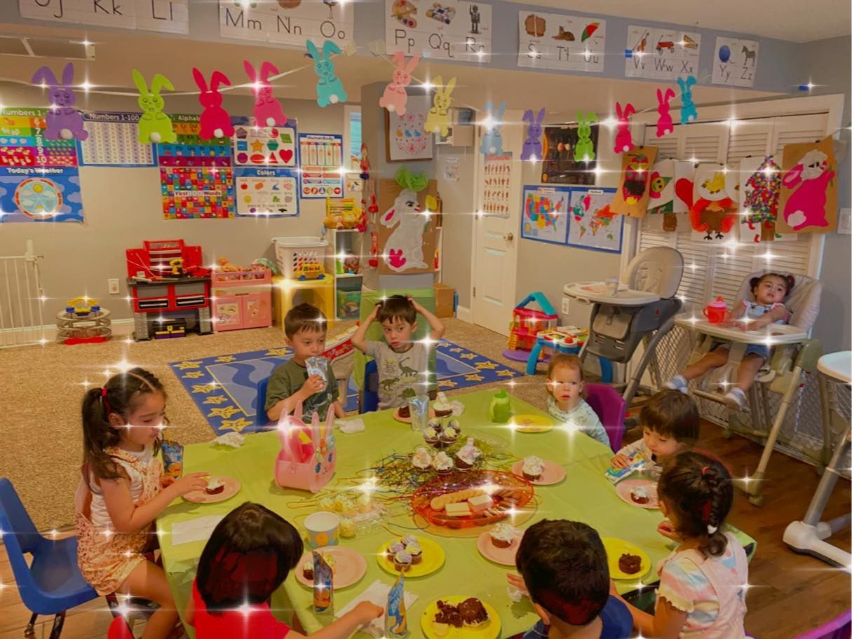 Children sitting around a table in a decorated classroom, celebrating a birthday with snacks and crafts