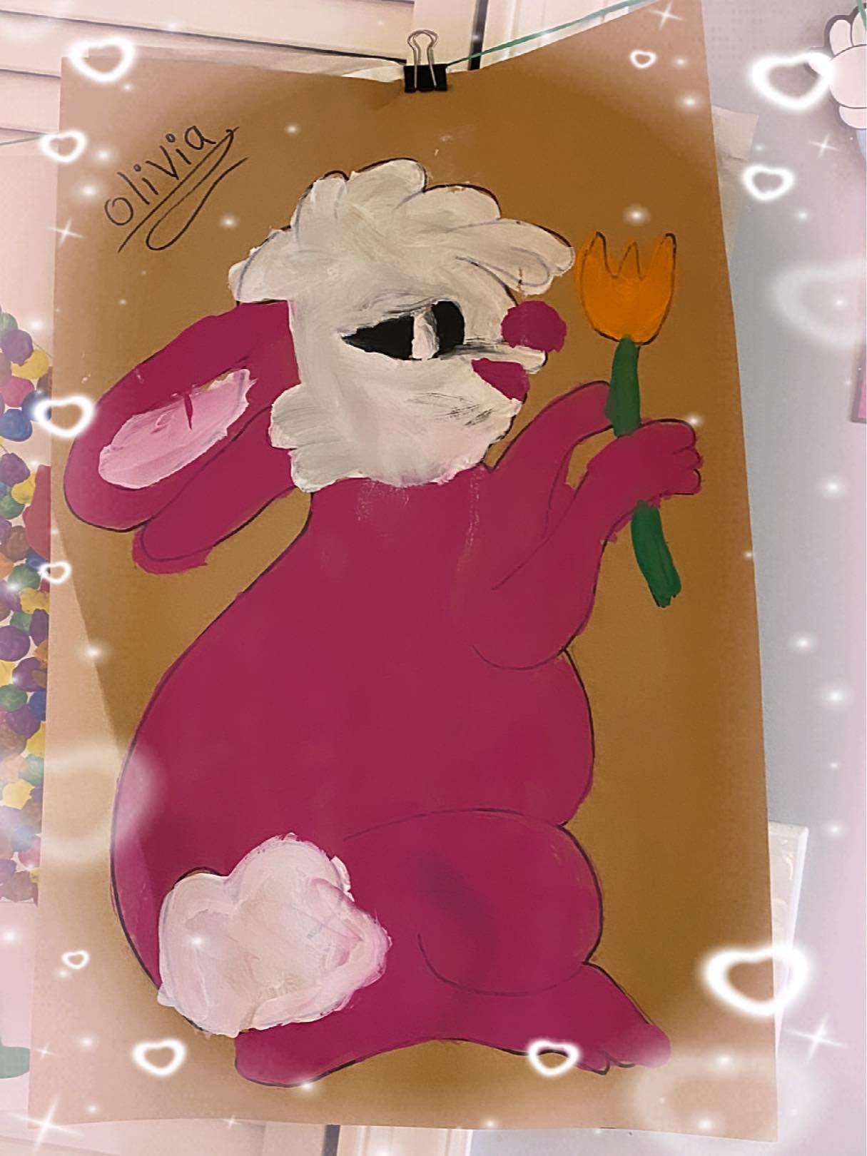 Purple rabbit painting holding an orange flower on tan paper, with white border decorations
