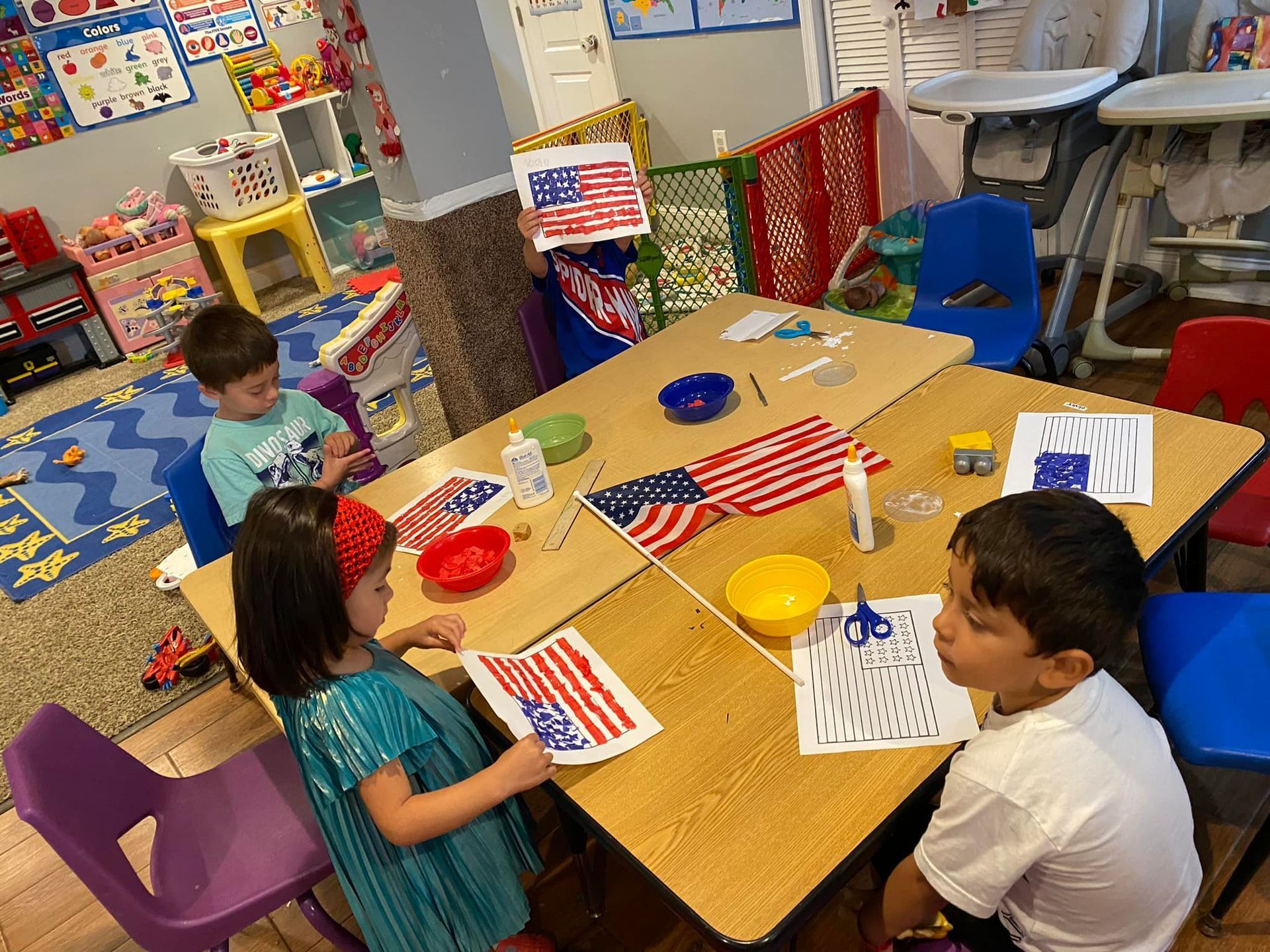 Children sitting around a table making patriotic crafts with small American flags in a classroom