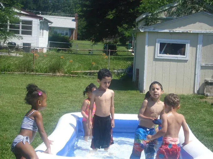 Children playing in a small inflatable pool in a backyard on a sunny day