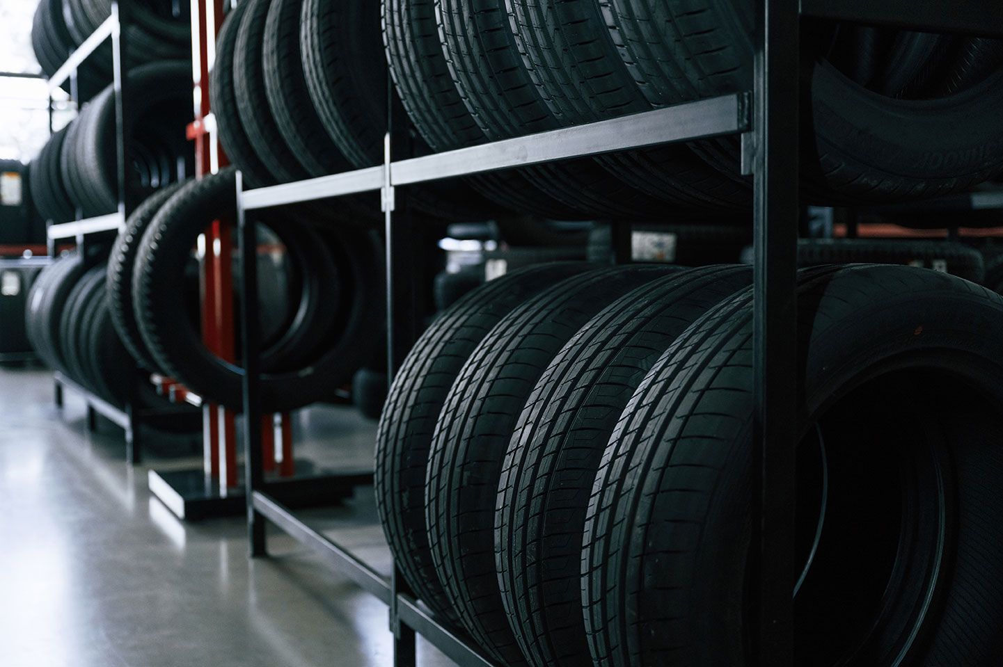 Black tires stacked on metal shelves inside a warehouse.