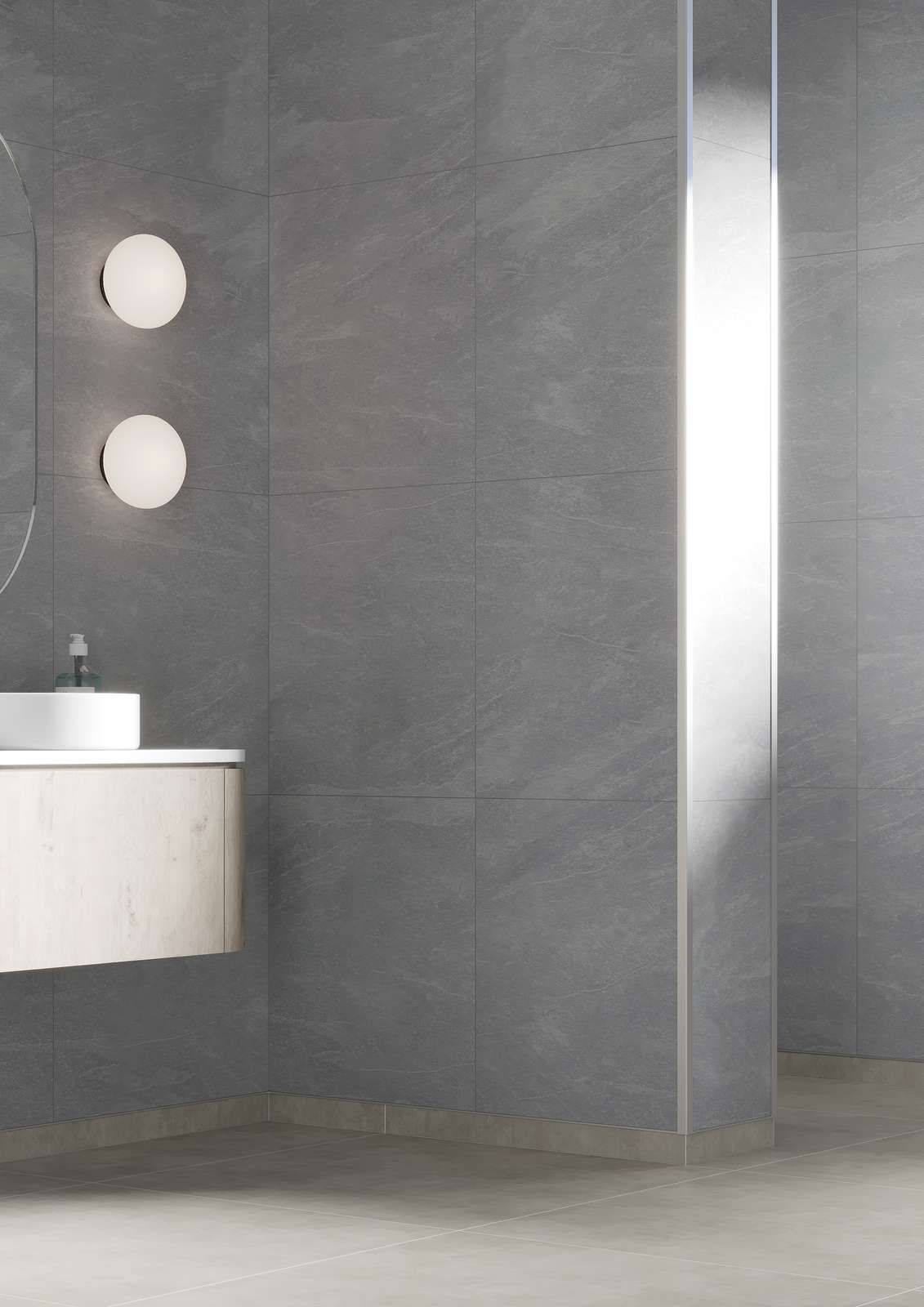 Modern bathroom with gray tiled walls, floating vanity, circular mirror, and two round sconces.