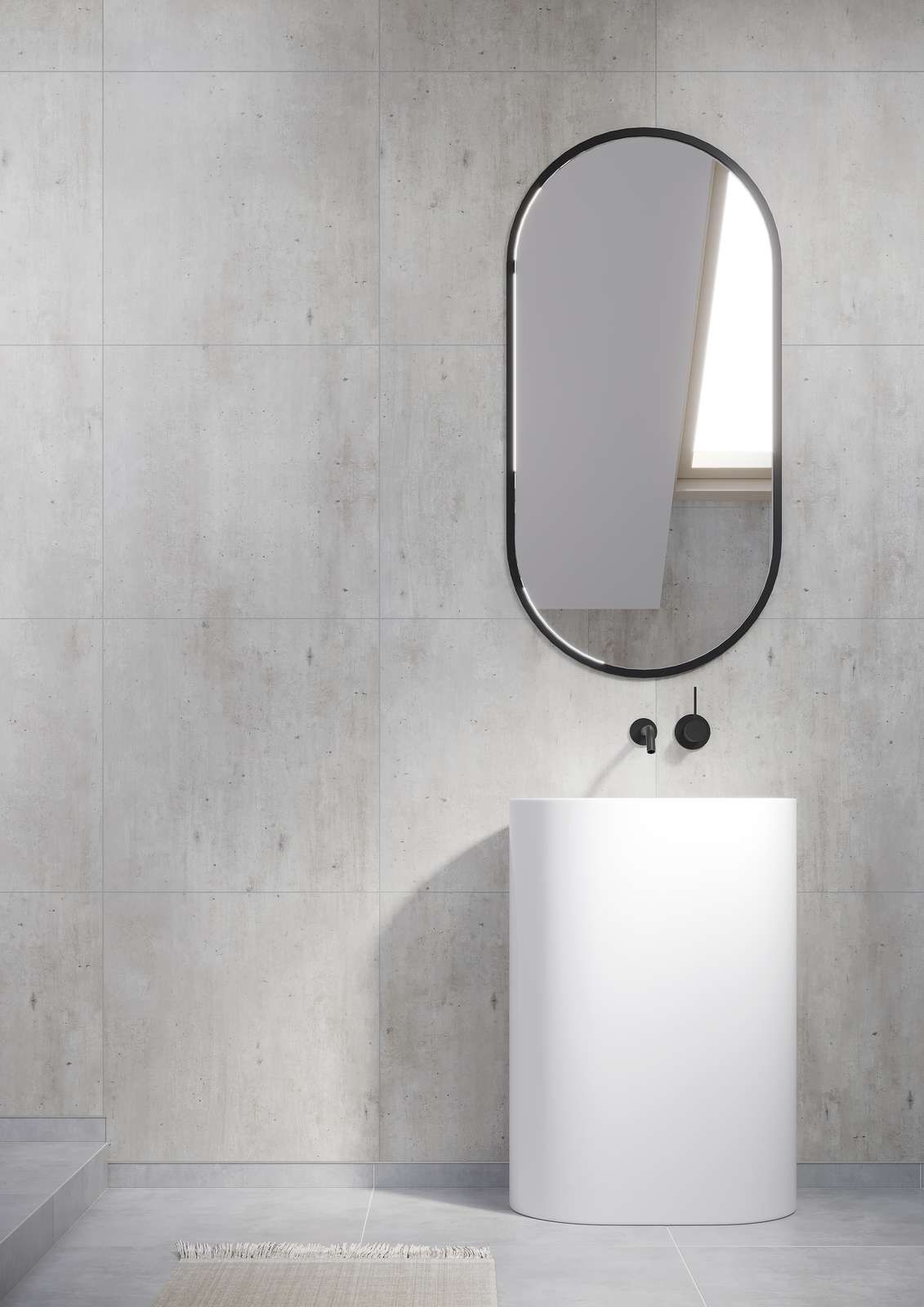 Modern white pedestal sink with black faucet and oval mirror against a light gray wall.