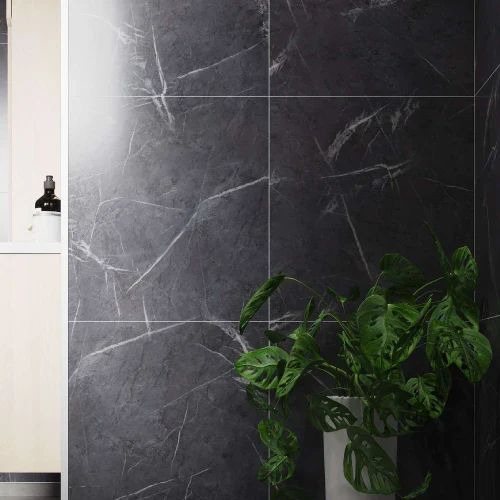Black marble tile wall with white veining, beside a light-colored cabinet and a plant.
