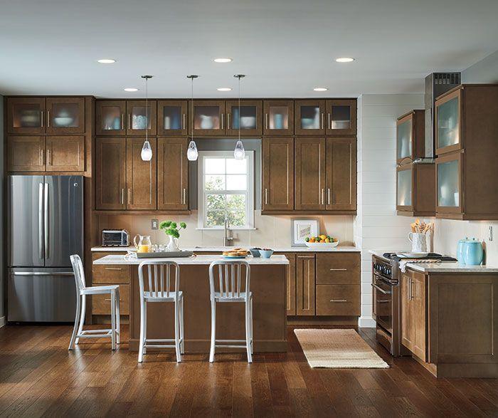 Modern kitchen with brown cabinets, stainless steel appliances, and island with bar stools.