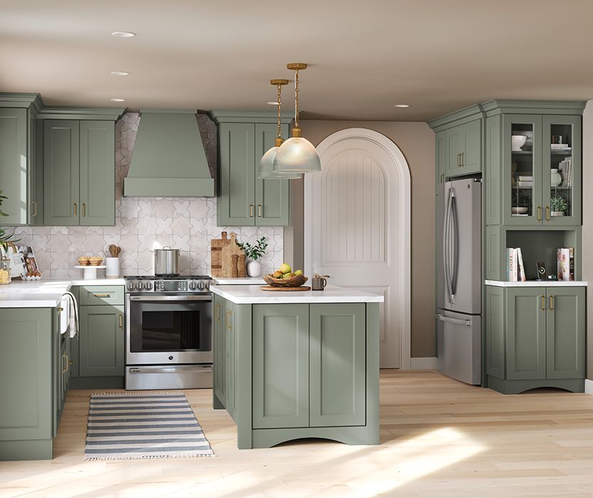 Green kitchen with island, stainless steel appliances, and white countertops.