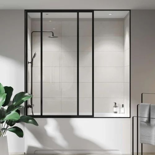 Shower enclosure with black frame and sliding glass doors, white tile, black shower fixtures, and a plant.