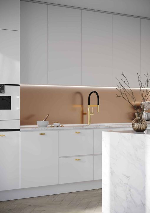 Modern kitchen with white cabinets, gold fixtures, and copper-colored backsplash.