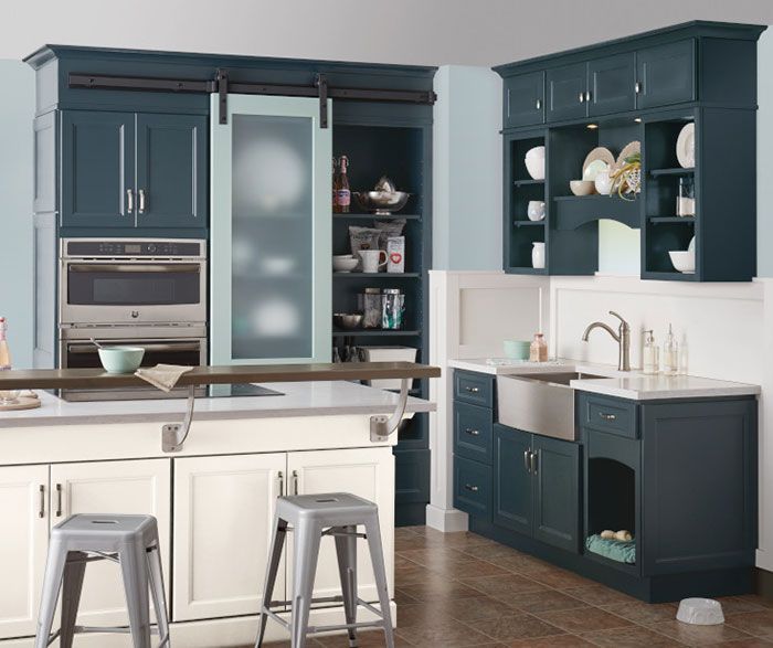 Blue and white kitchen with a farmhouse sink and pantry with a sliding door.